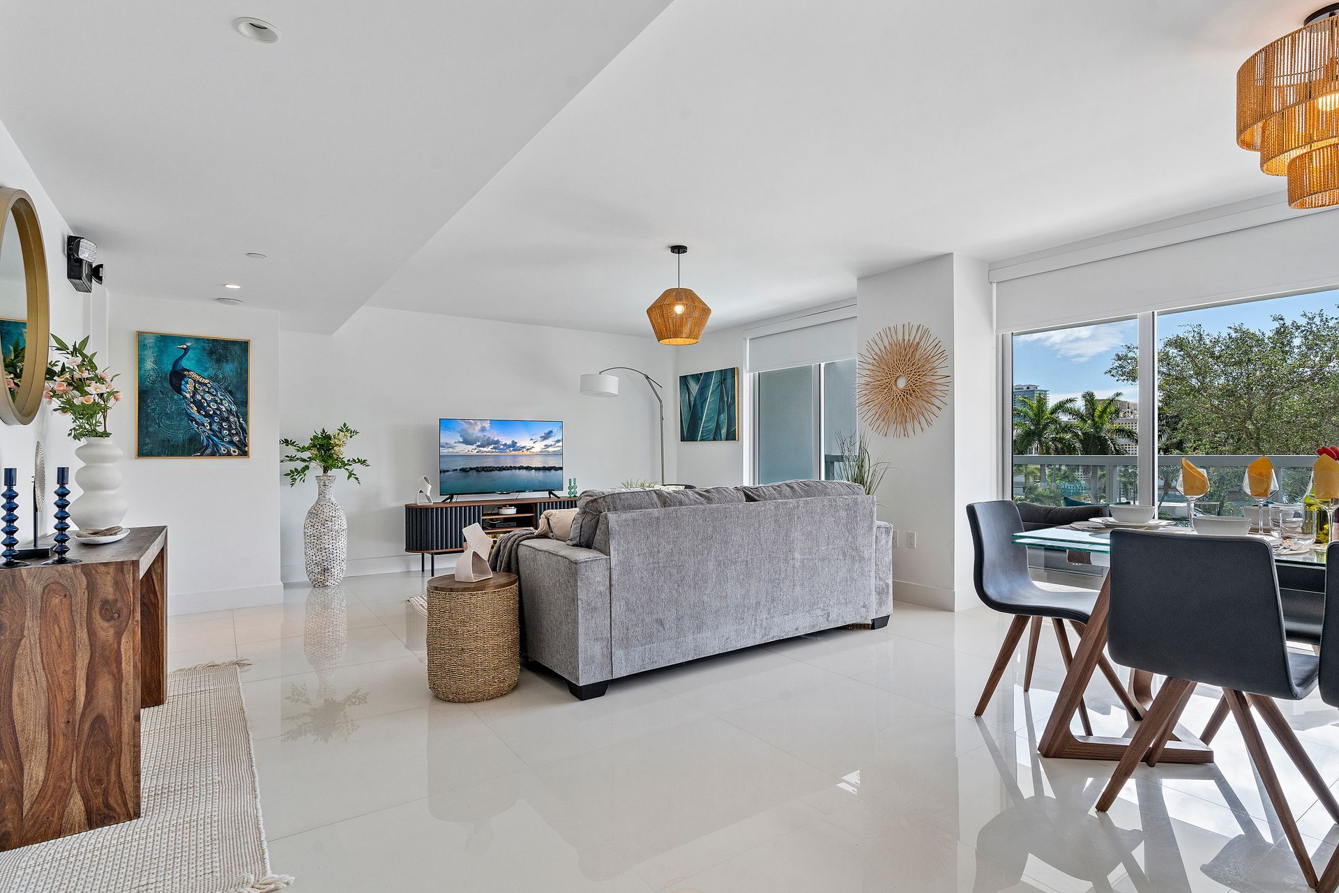 Bright, modern living space with gray couch, dining table, and views.