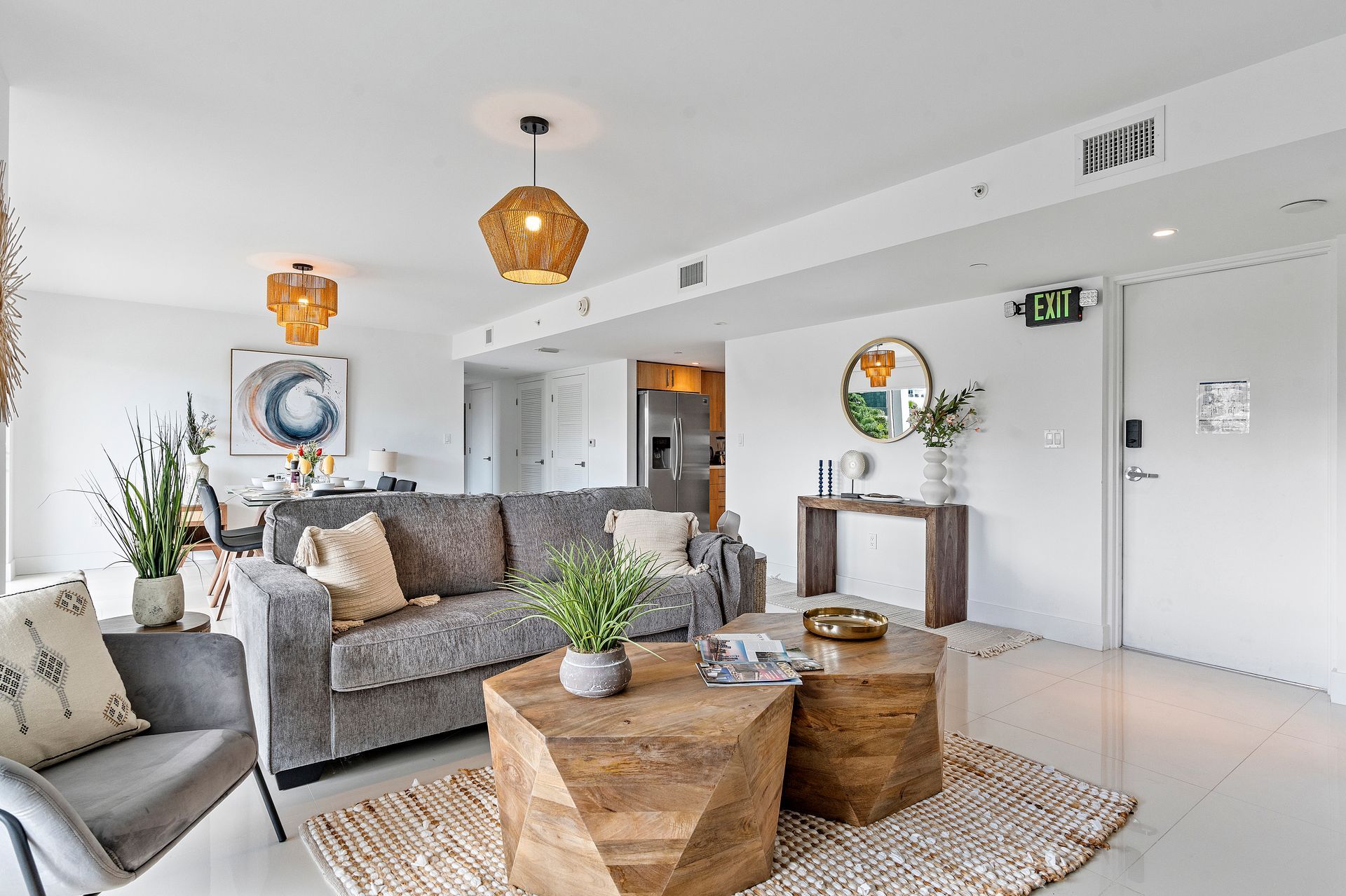 Modern living room with gray sofa, wooden tables, and woven pendant lights.