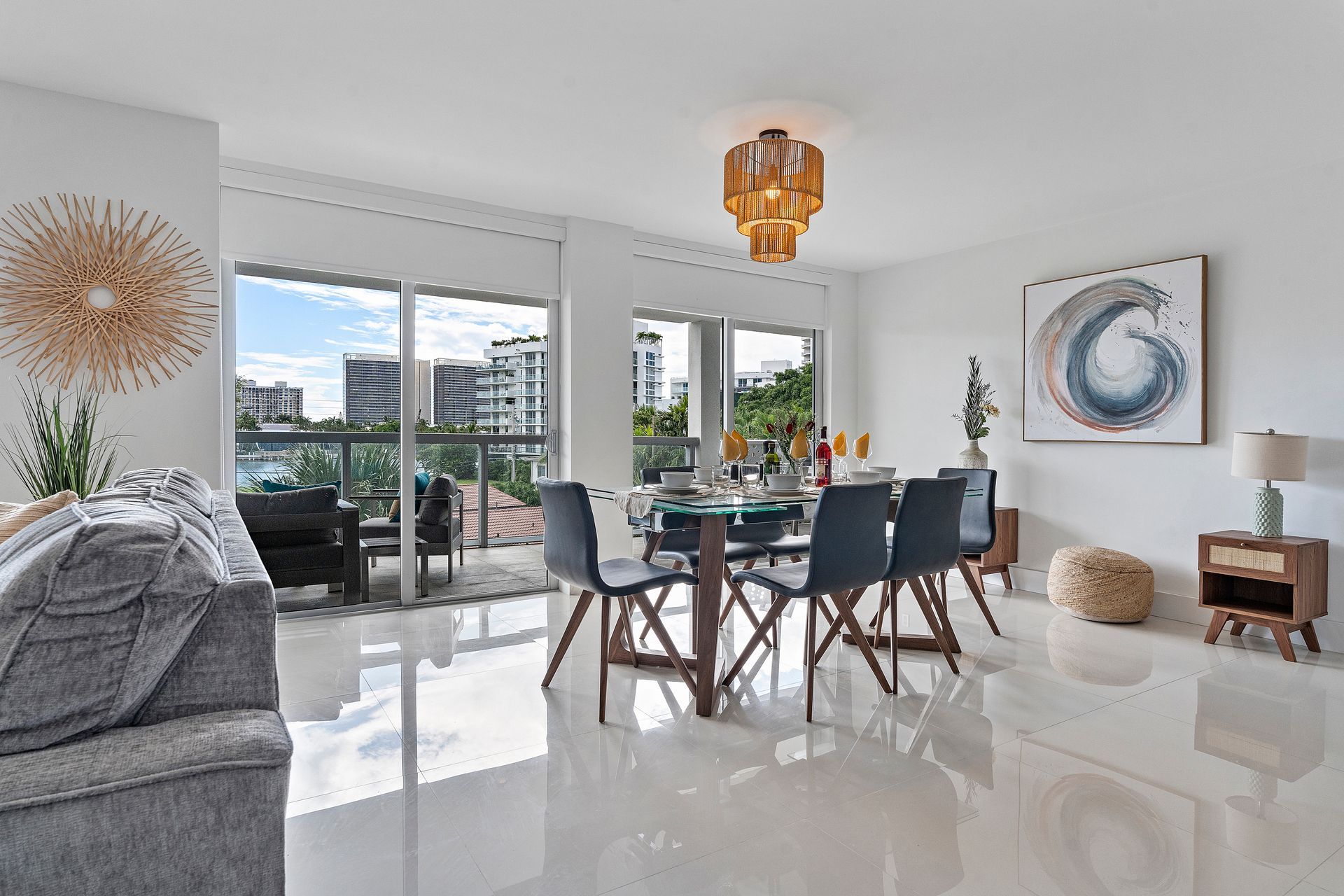Bright dining room with a wooden table and chairs, large windows, and a decorative light fixture.