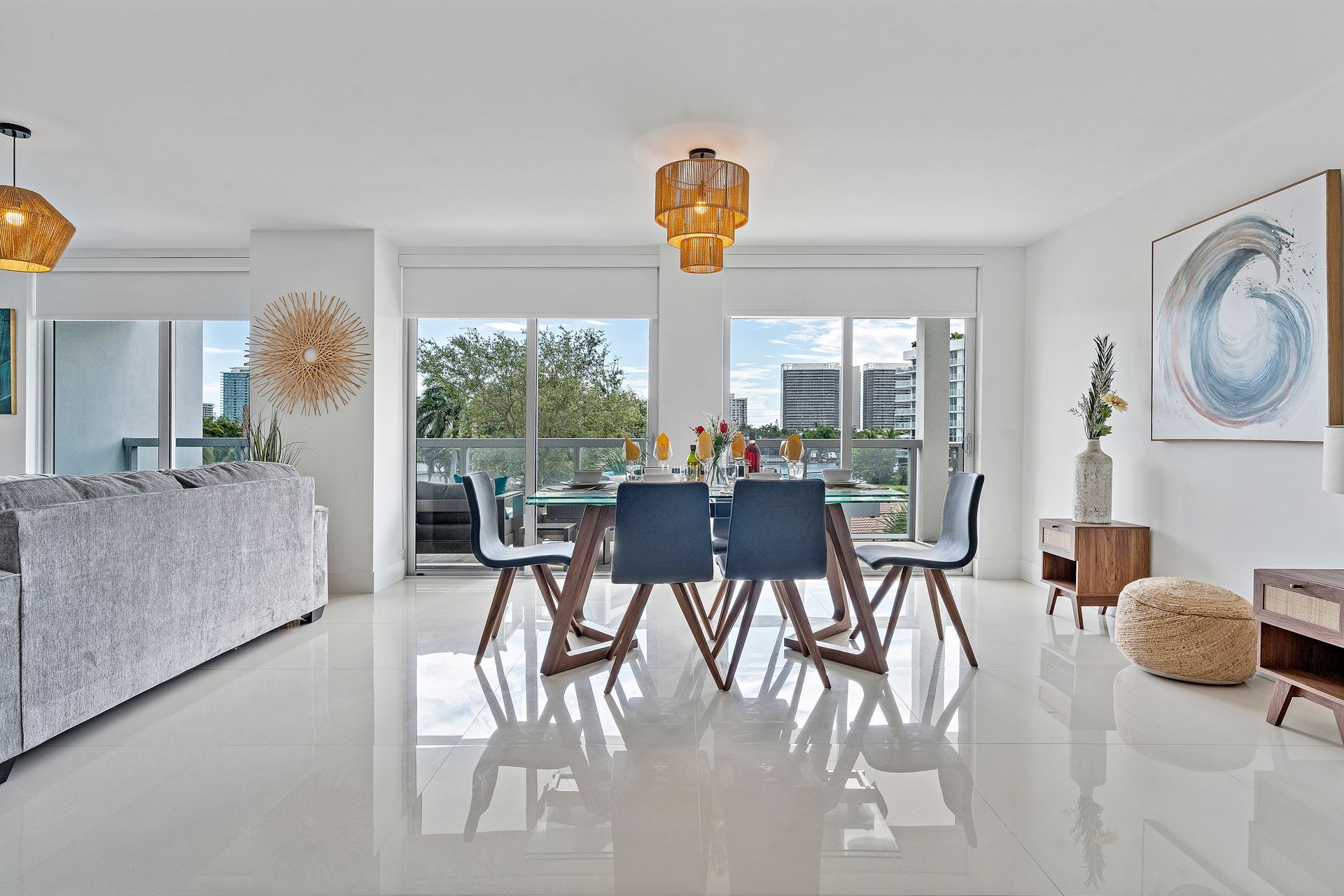 Bright dining area with table set for a meal, blue chairs, and large windows overlooking a cityscape.