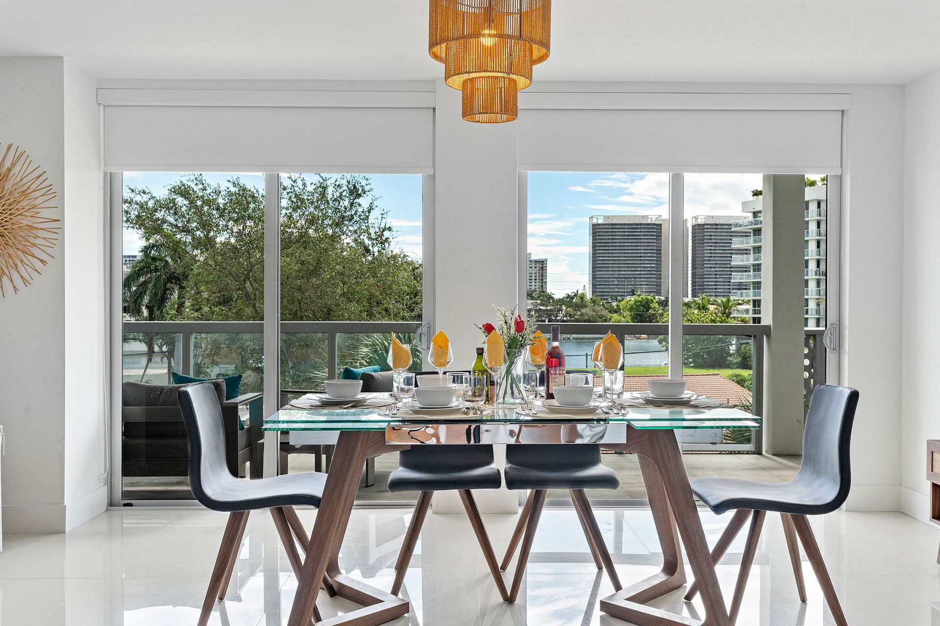 Dining room with glass table set for a meal, looking out large windows with a city view.