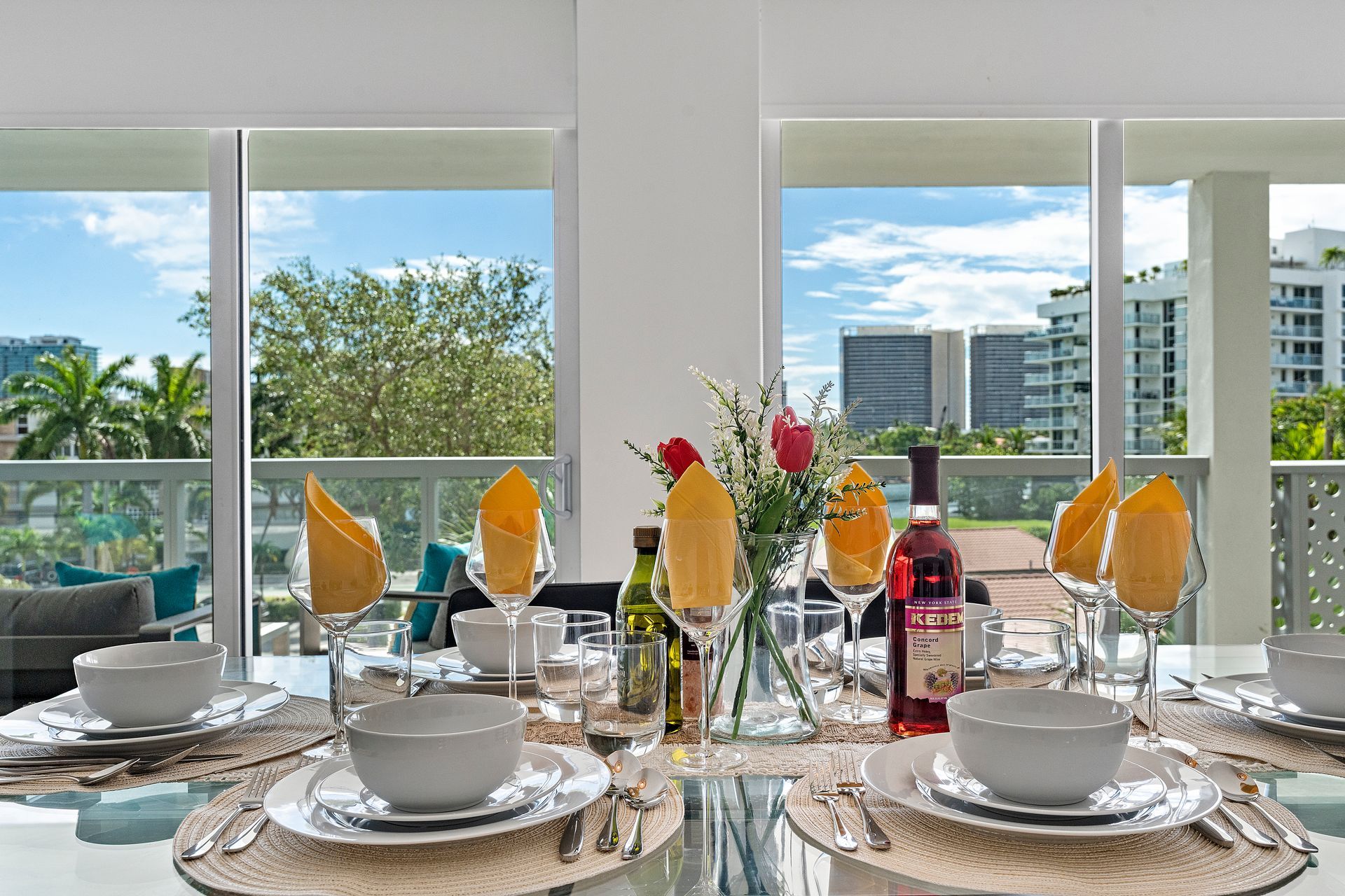 Dining table set for a meal, overlooking cityscape through large windows.