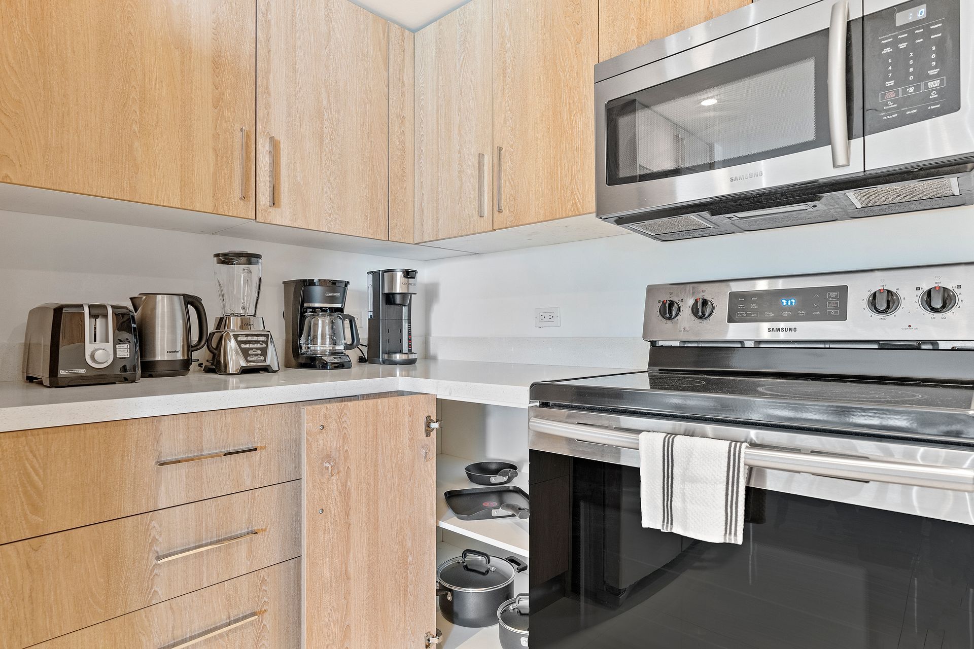 Kitchen corner with appliances on countertop, including toaster, blender, coffee maker, and microwave above a stove.