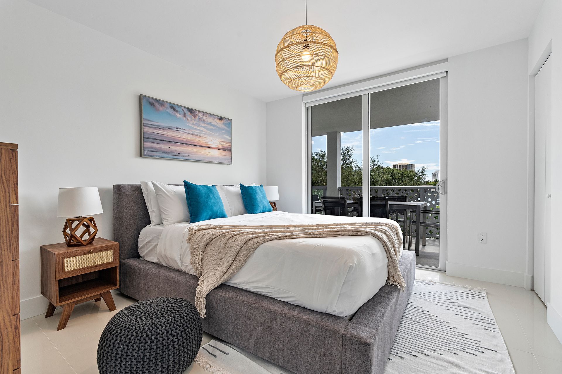 Bedroom with a bed, nightstand, and balcony access. Blue, white, and tan decor.