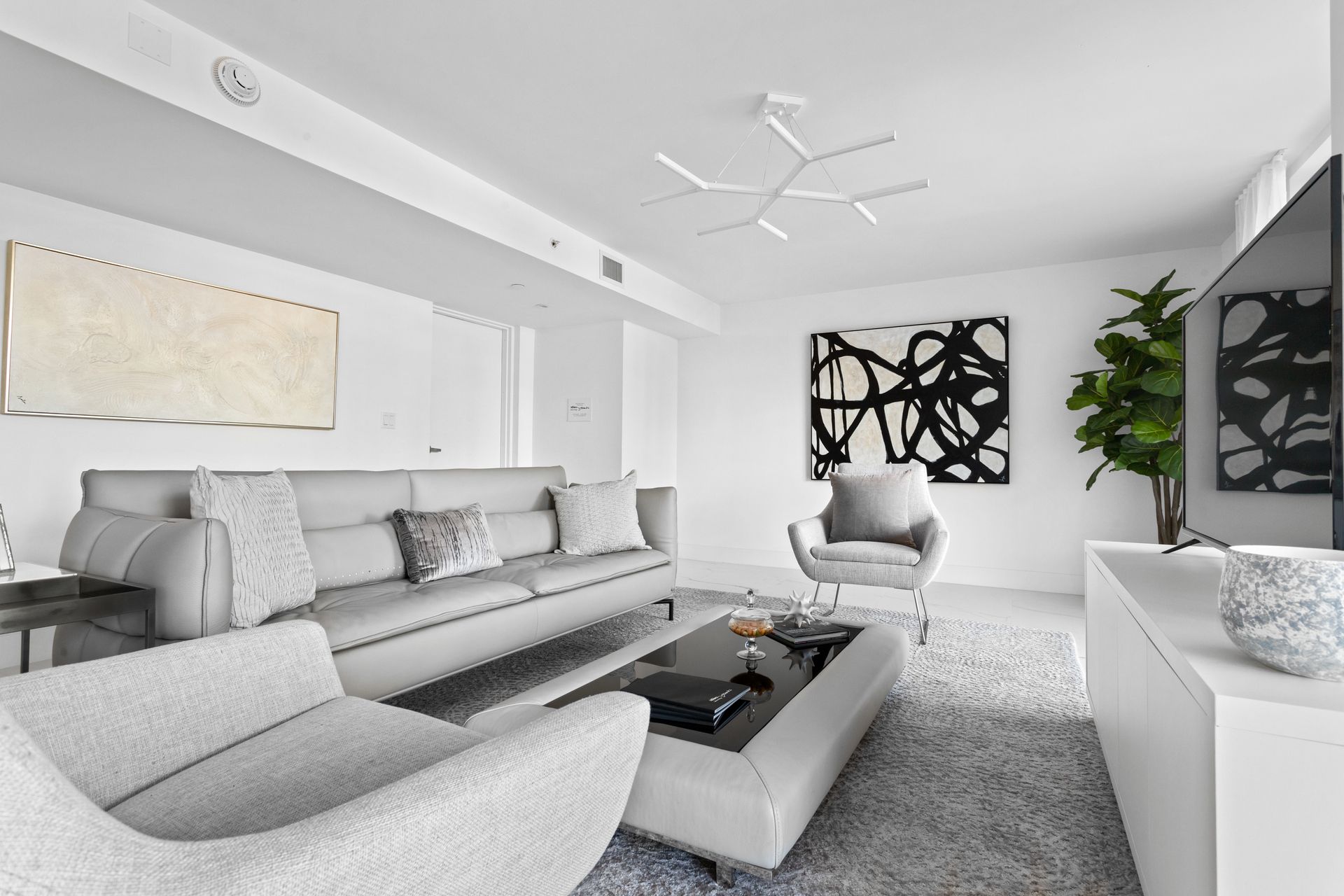 Modern living room with gray furniture, abstract art, and white walls.