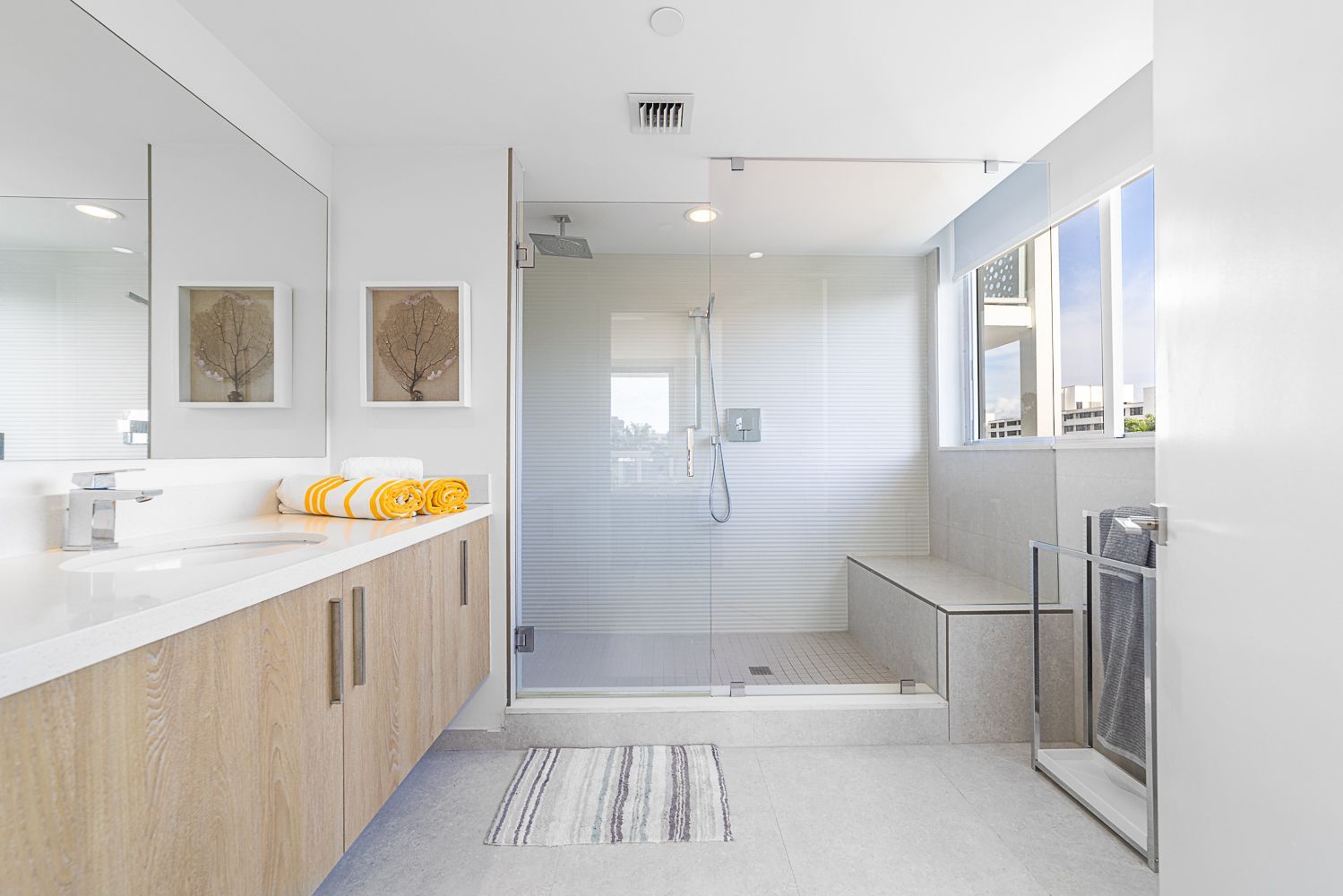 Modern bathroom with a glass shower, white walls, and light wood vanity.