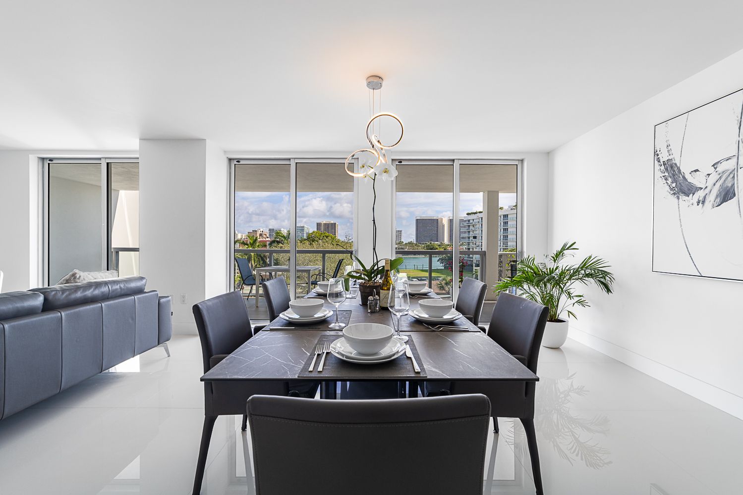 Dining room with dark table, chairs, place settings, and a view of a city.