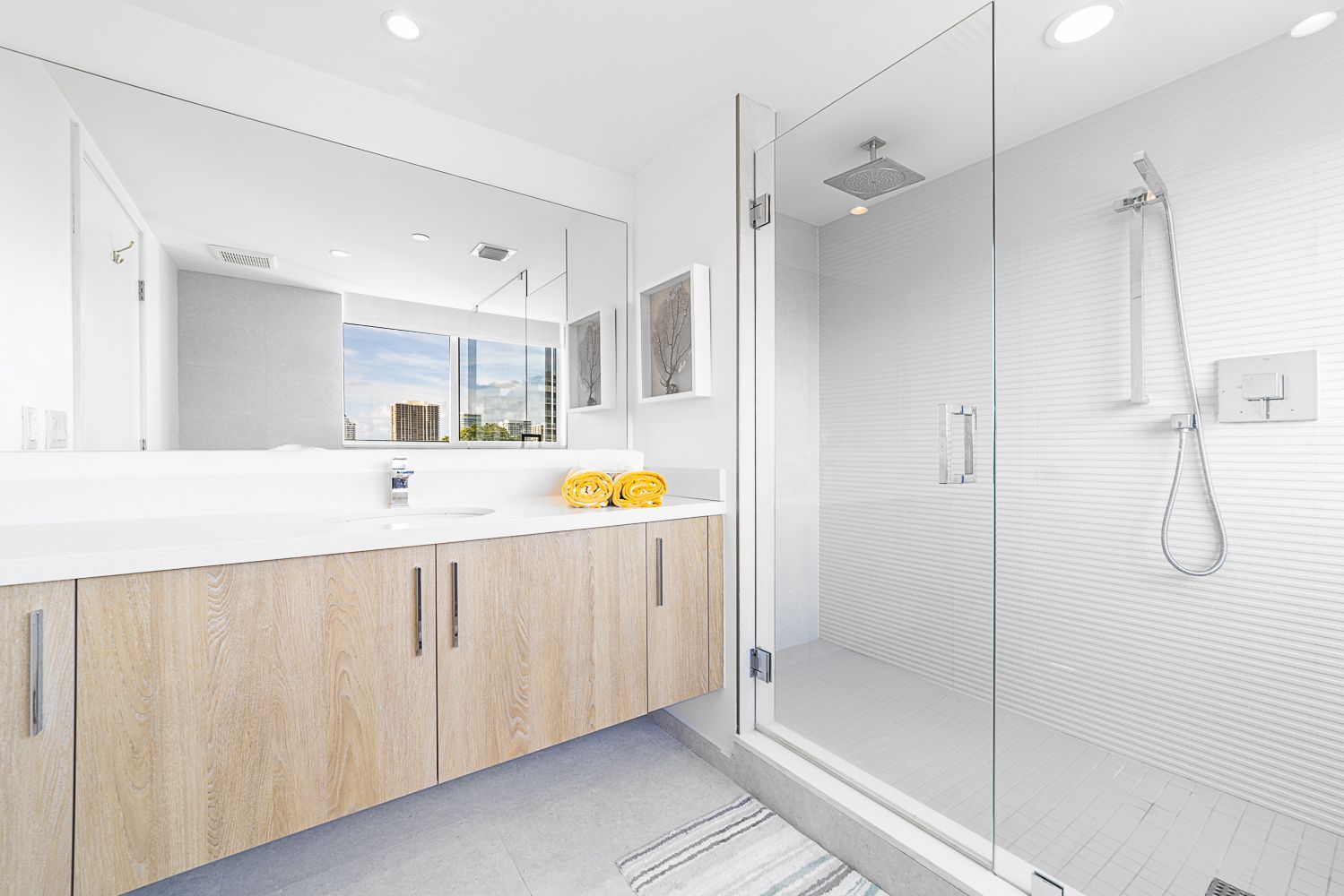 Modern bathroom with glass shower, light wood vanity, and large mirror.