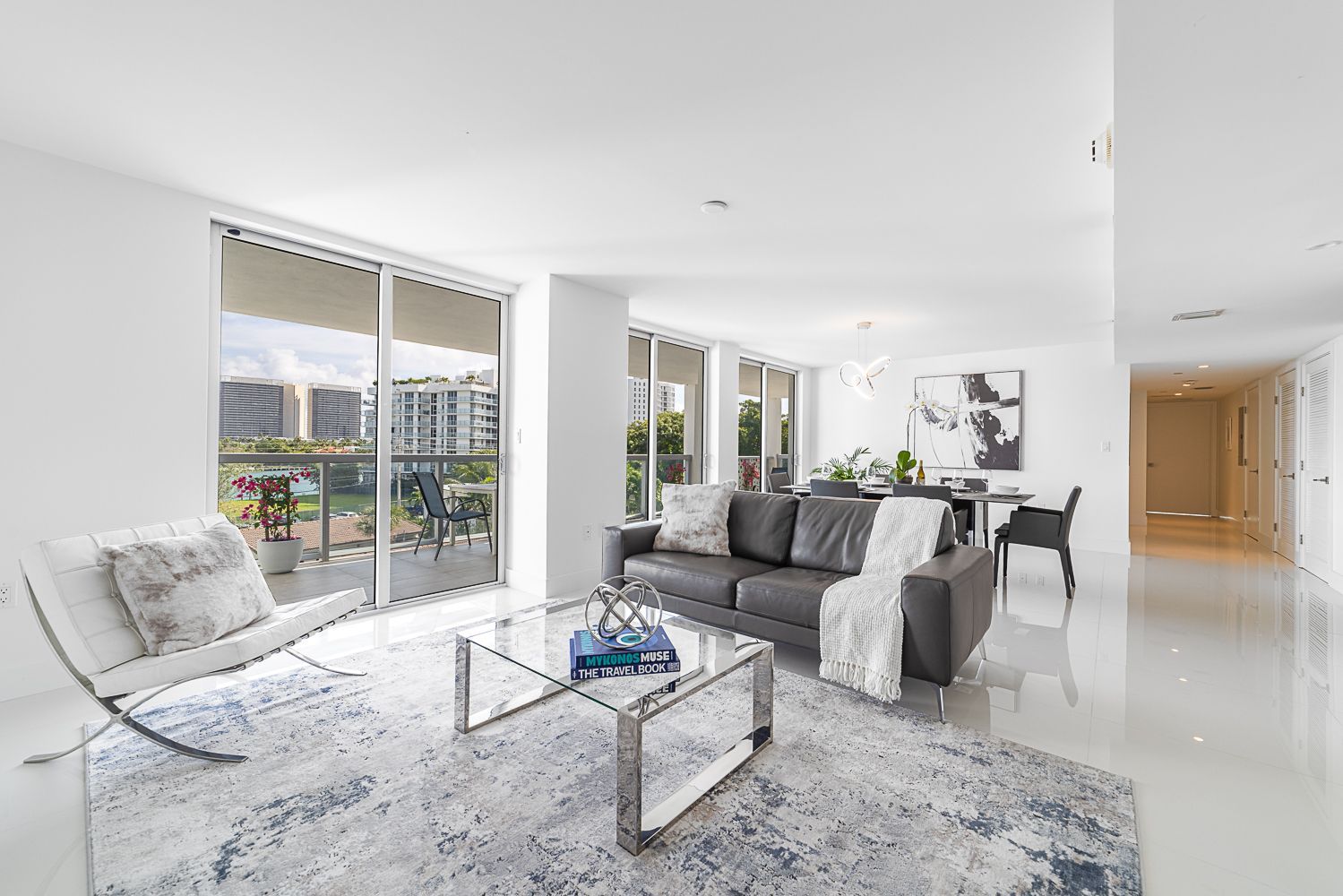 Spacious modern living room with a gray sofa, glass coffee table, and balcony access.