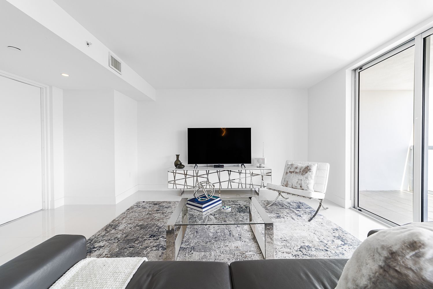 Modern living room with white walls, furniture, and a large window.