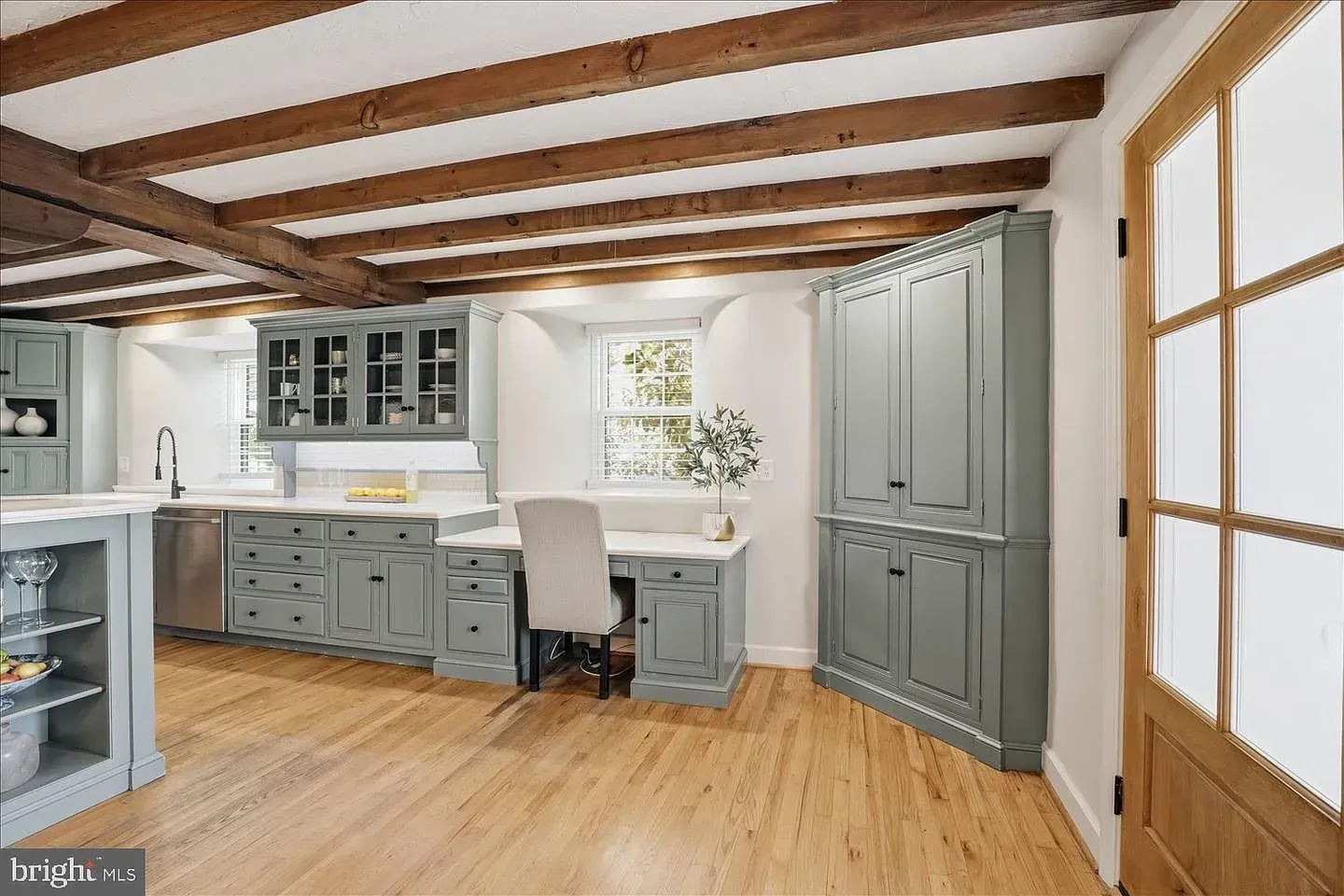 Modern home office with gray built-ins, wood beams, and light wood floors