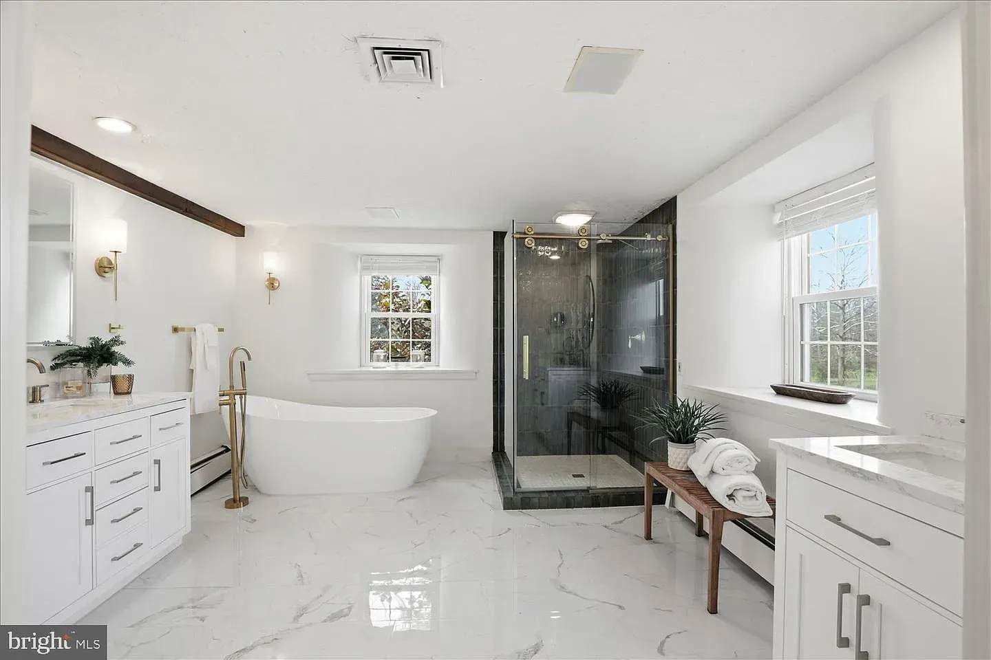 Bright white modern bathroom with freestanding tub, glass shower, vanity, and windows
