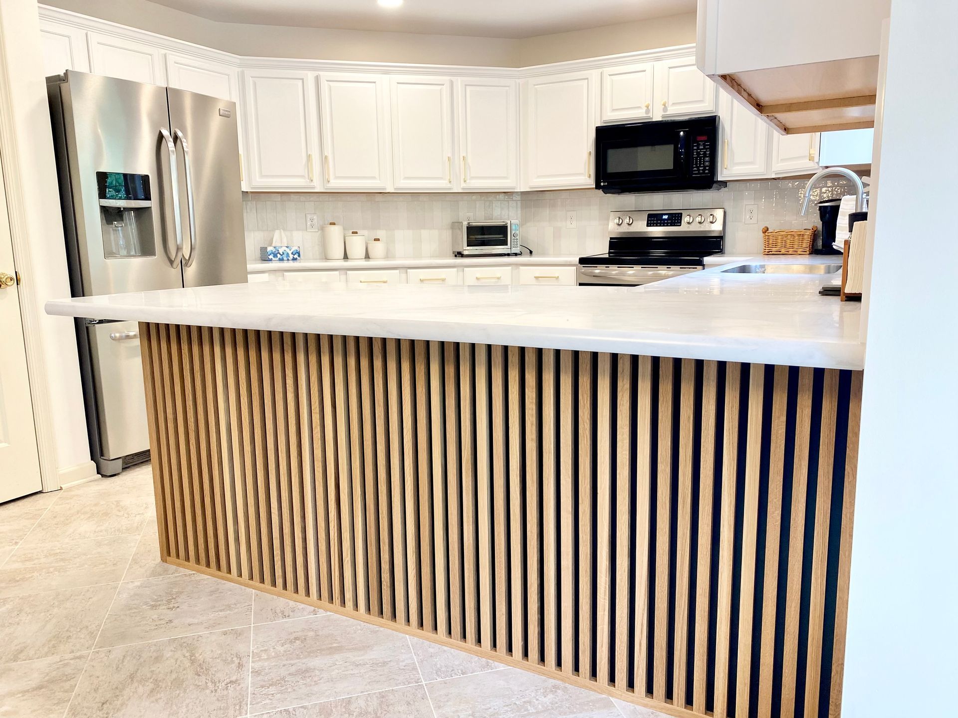 a kitchen with white cabinets , stainless steel appliances , and a wooden island .