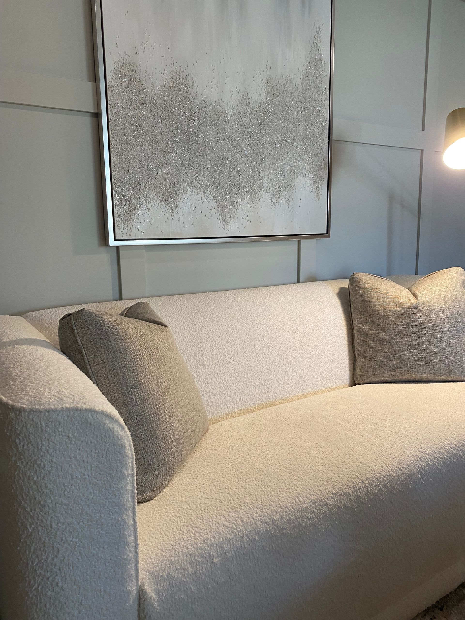 a white custom Christy Martin couch with pillows and a painting on the wall above it .