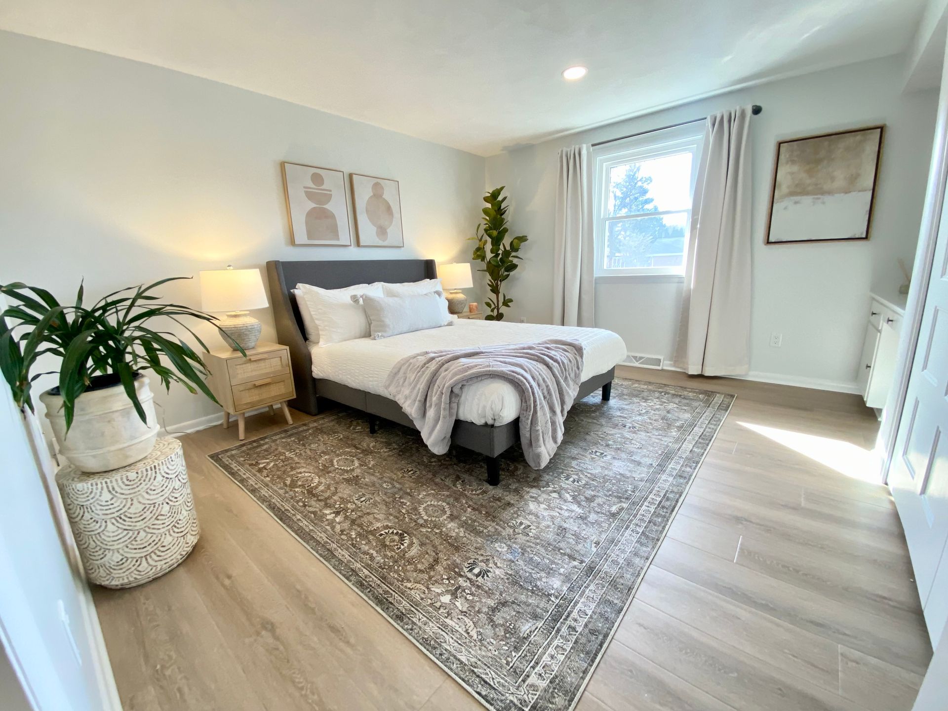 a beautiful bedroom with a bed , nightstand , rug and window .