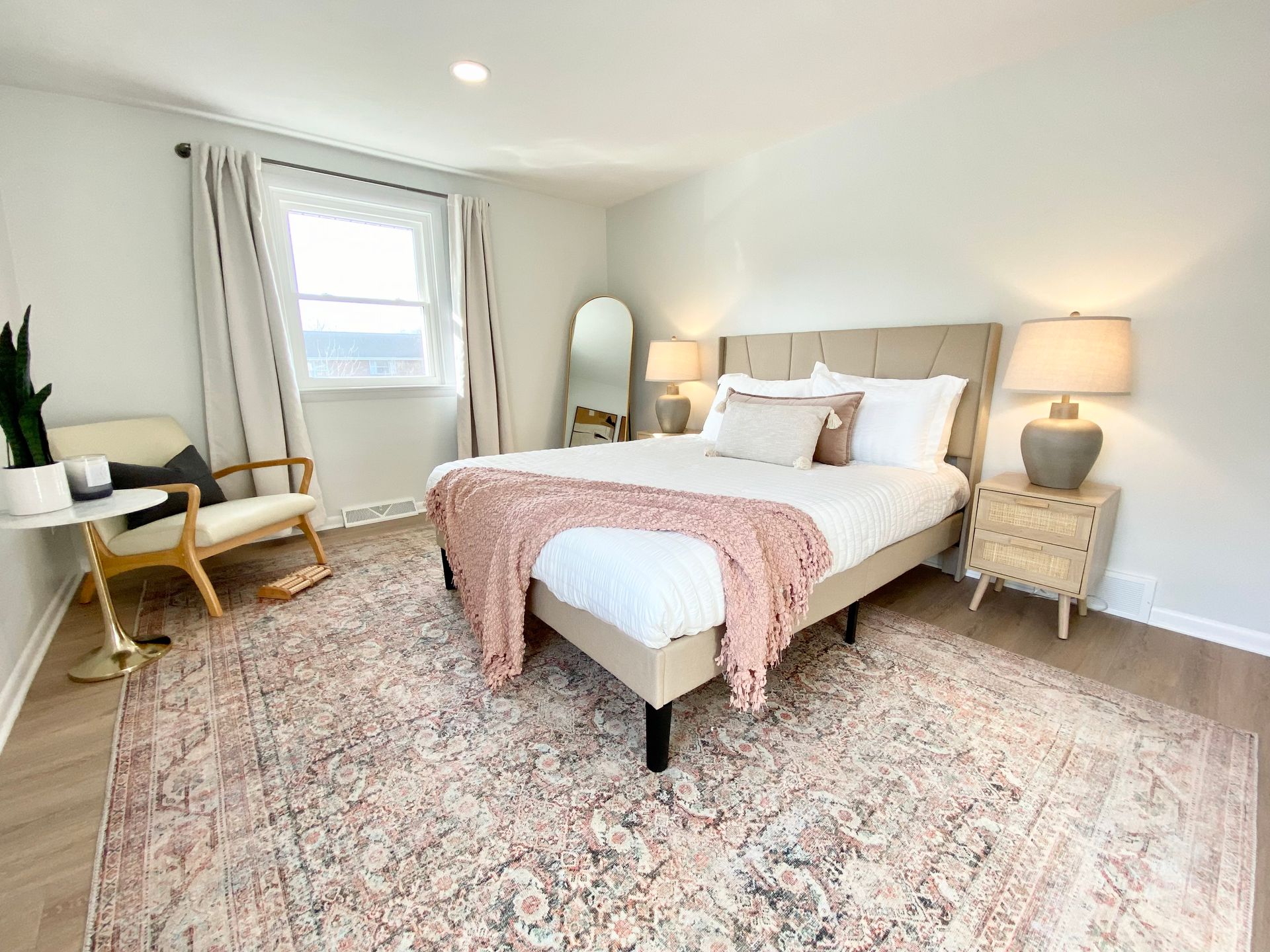 a bedroom with a bed , chair , nightstand and rug .