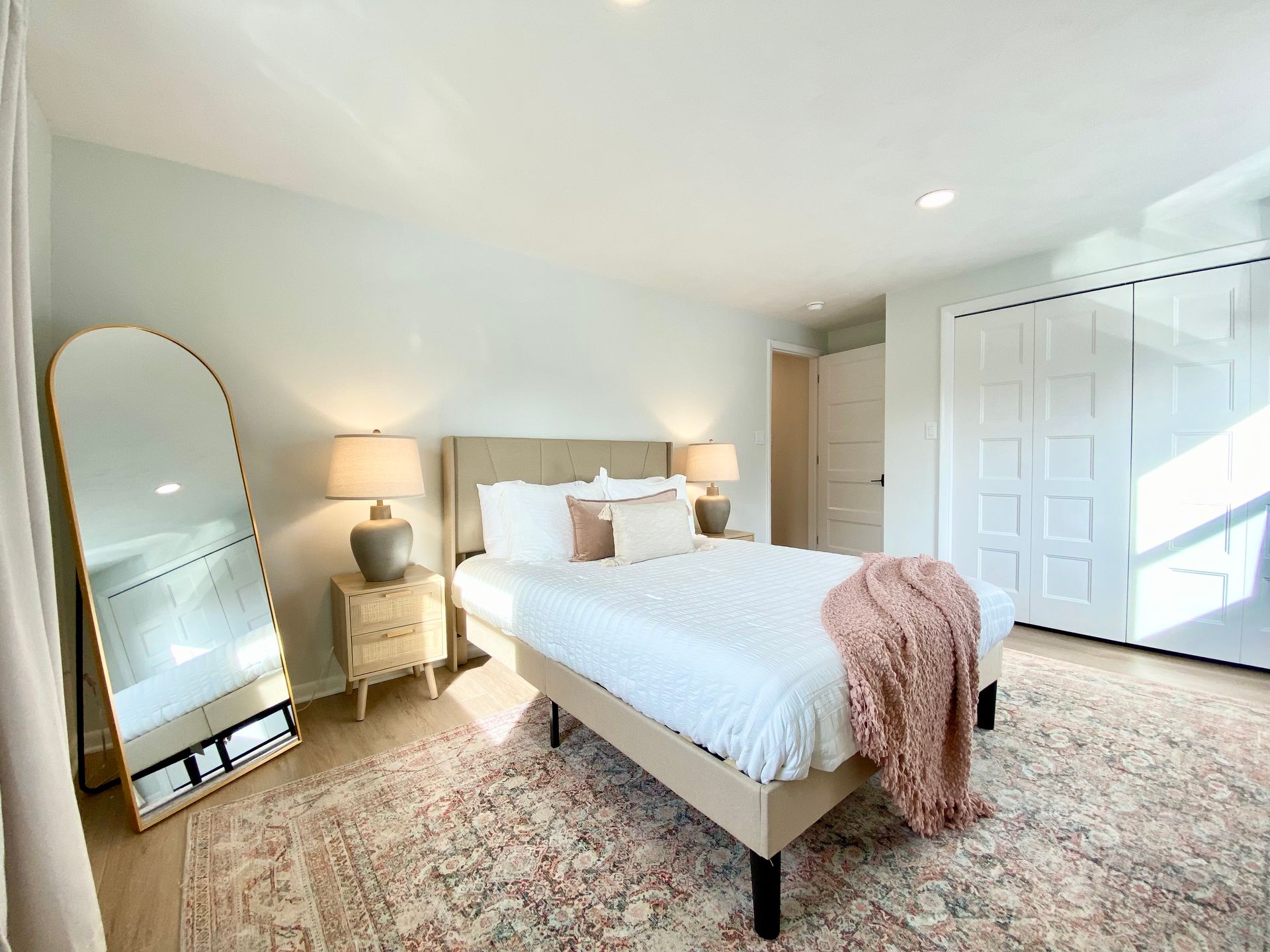 a bedroom with a bed , nightstand , mirror and rug .