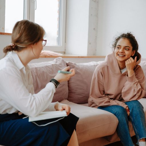 Female psychologist with young girl patient sitting on couch