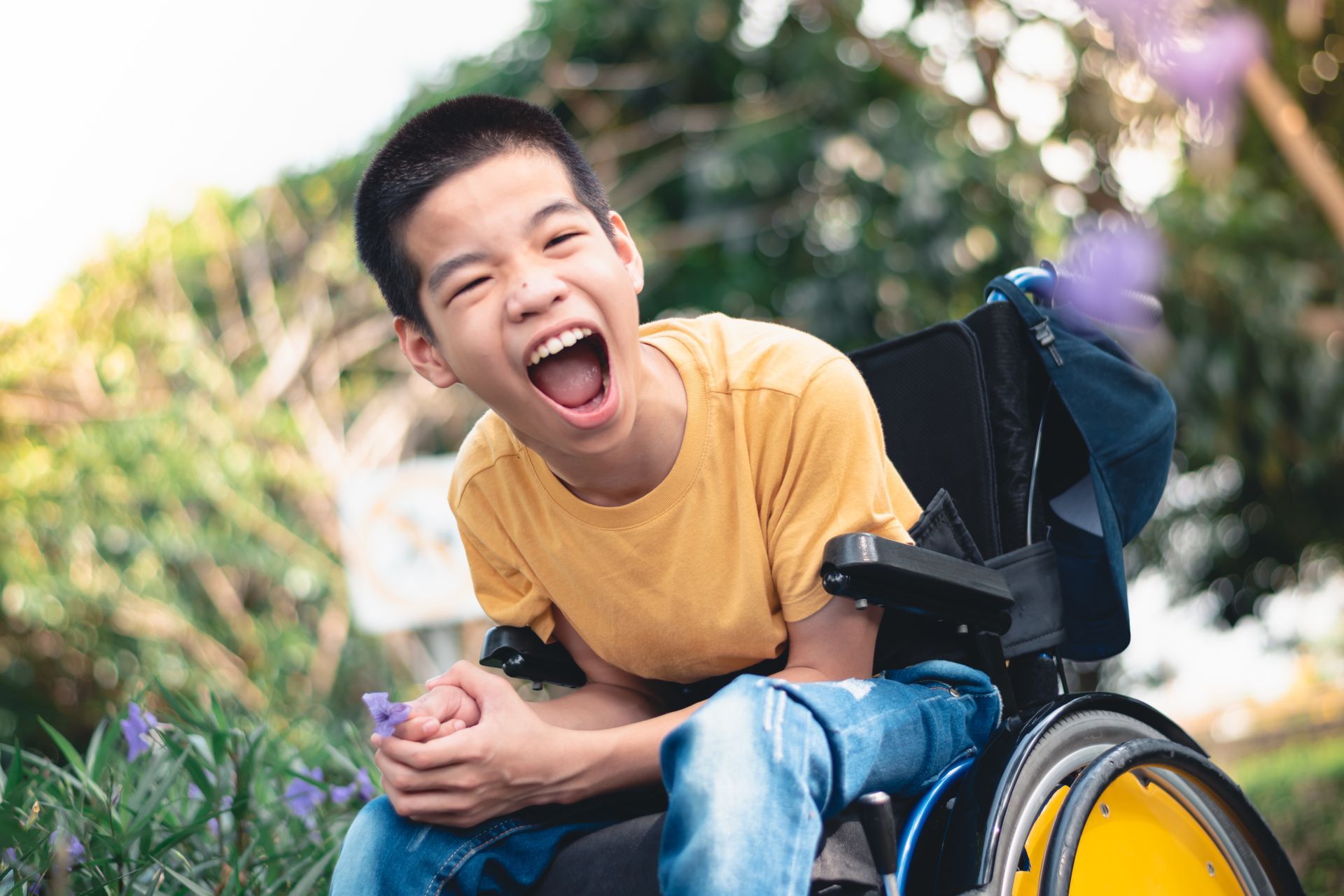 Young male NDIS participant in wheel chair wearing yellow shirt smiling - helps continuity of care