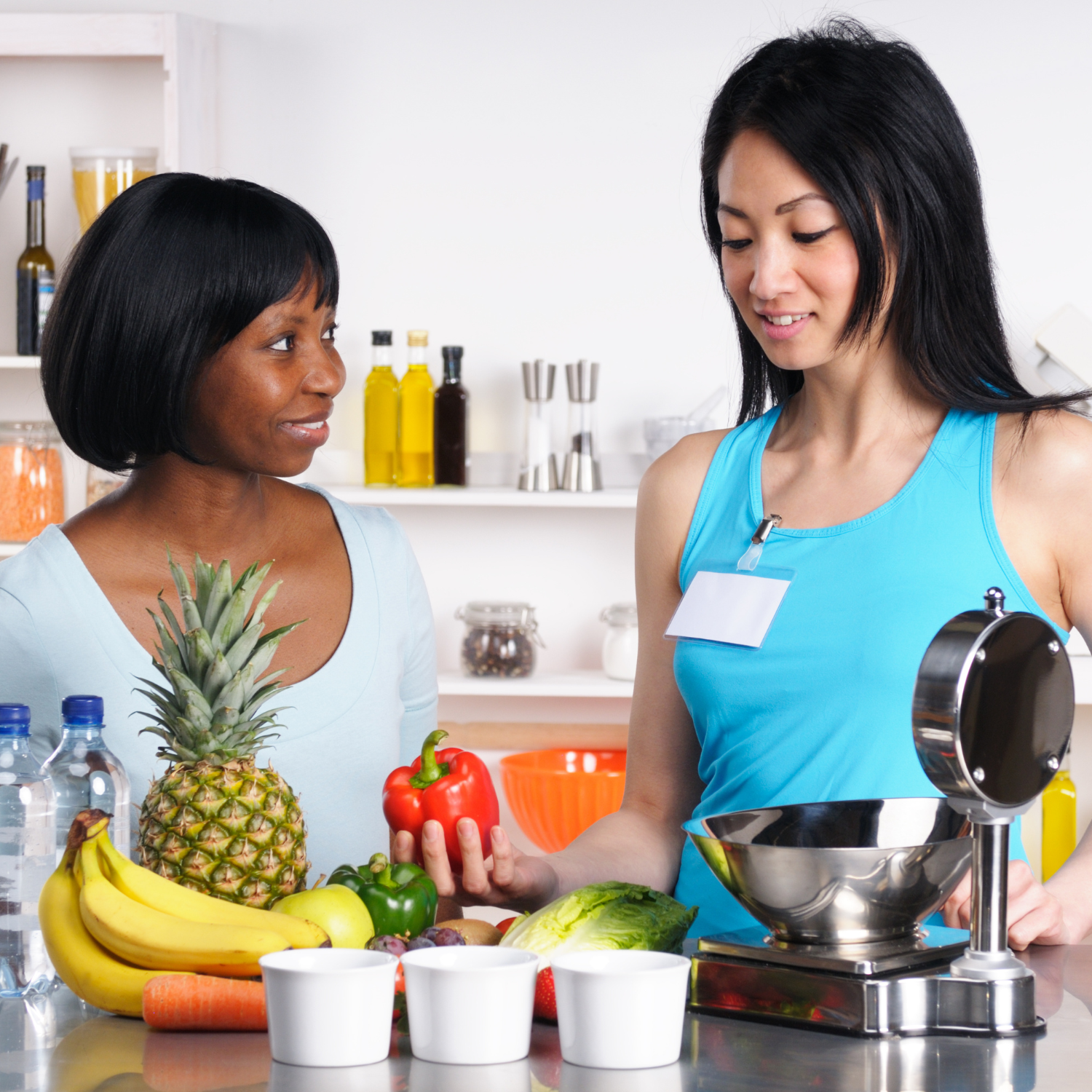 Female dietitian talking to female patient, with assortment of fruits and vegetables in front of them