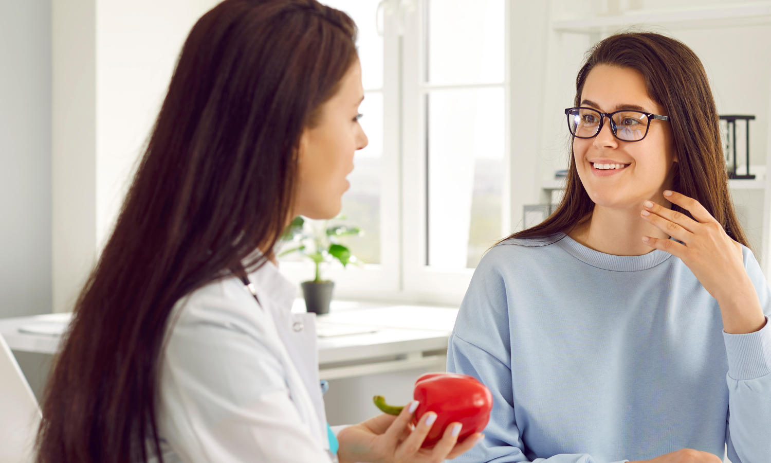 Female dietitian holding a red bell pepper while talking to patient