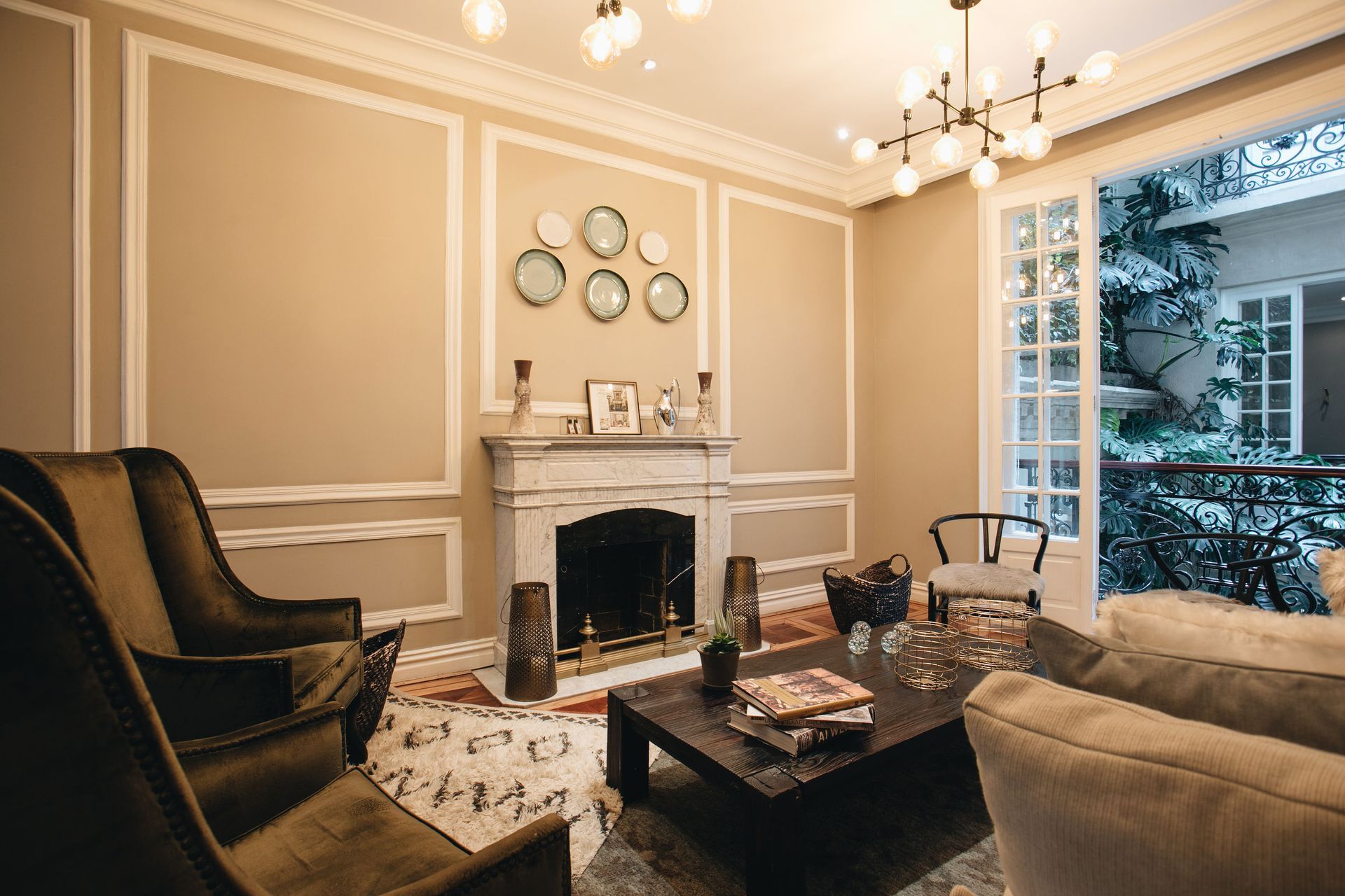 A living room with a fireplace , chairs , a coffee table and a chandelier.