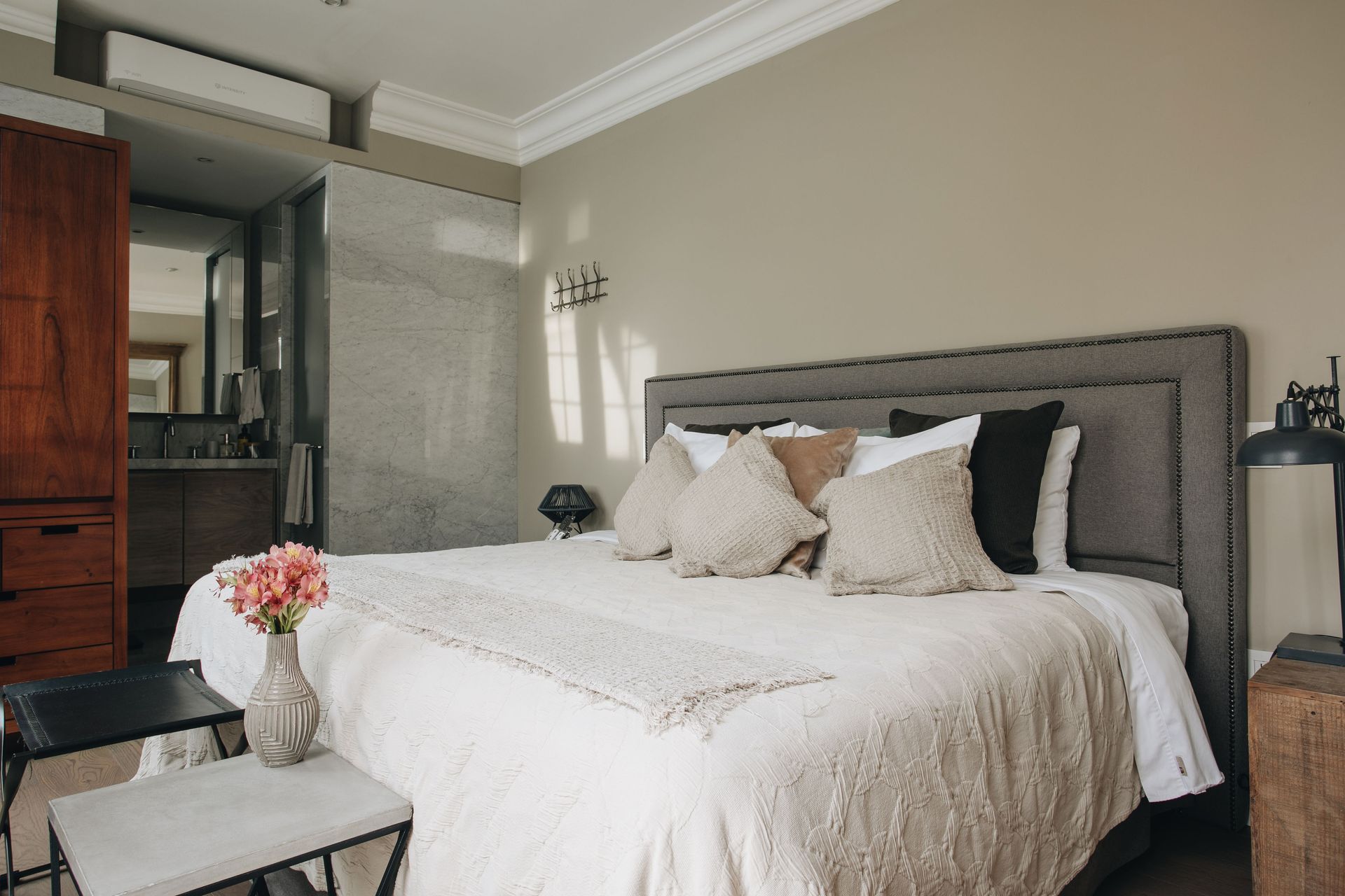 A bedroom with a large bed and a vase of flowers on the bed.