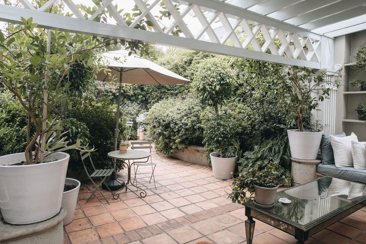 A patio with a table , chairs , umbrella and potted plants.