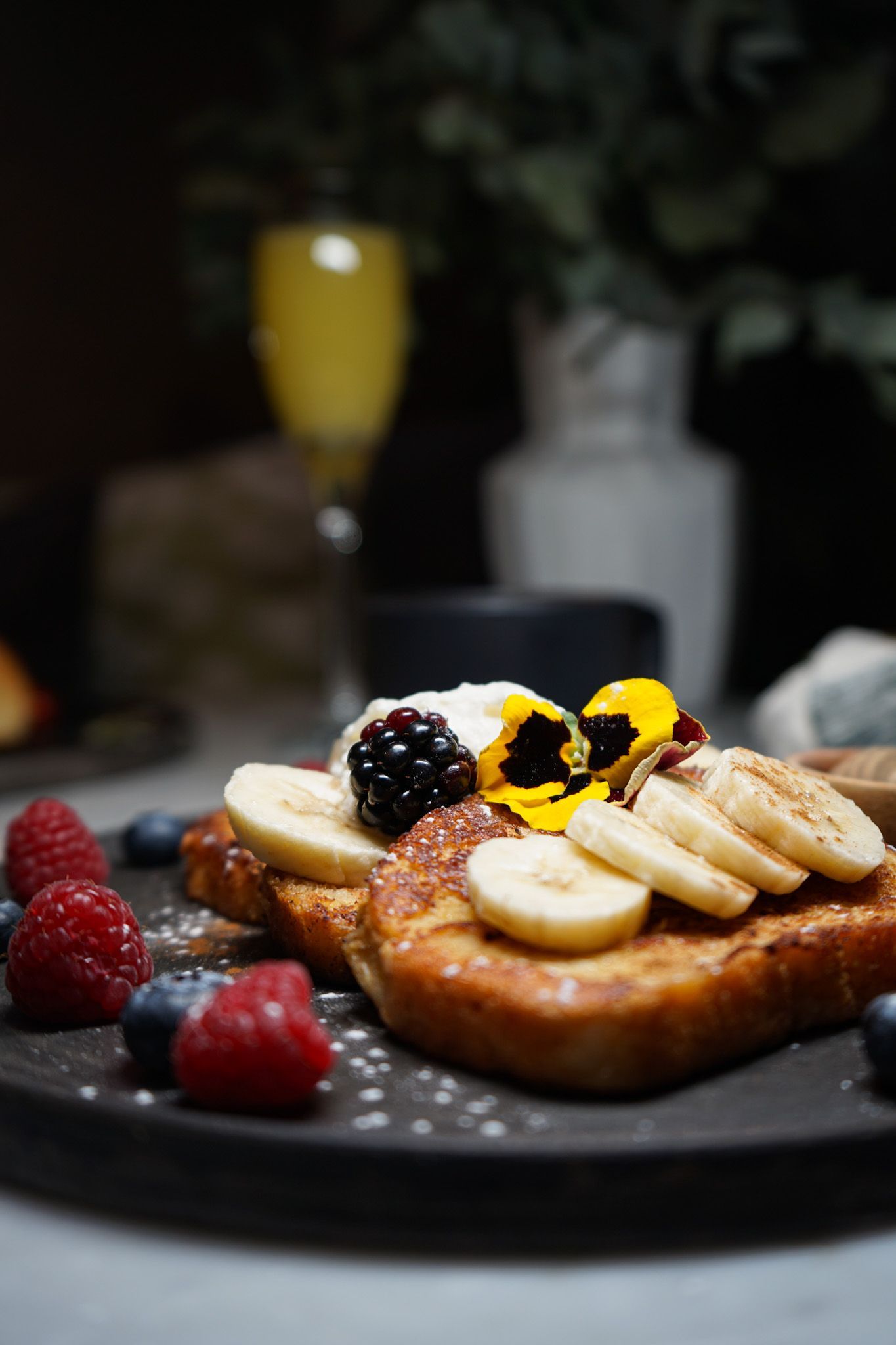 French toast with bananas , raspberries and blueberries on a plate.