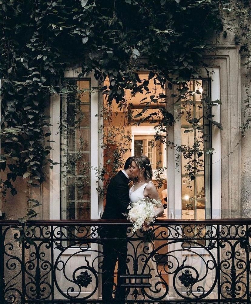 A bride and groom are kissing on a balcony.