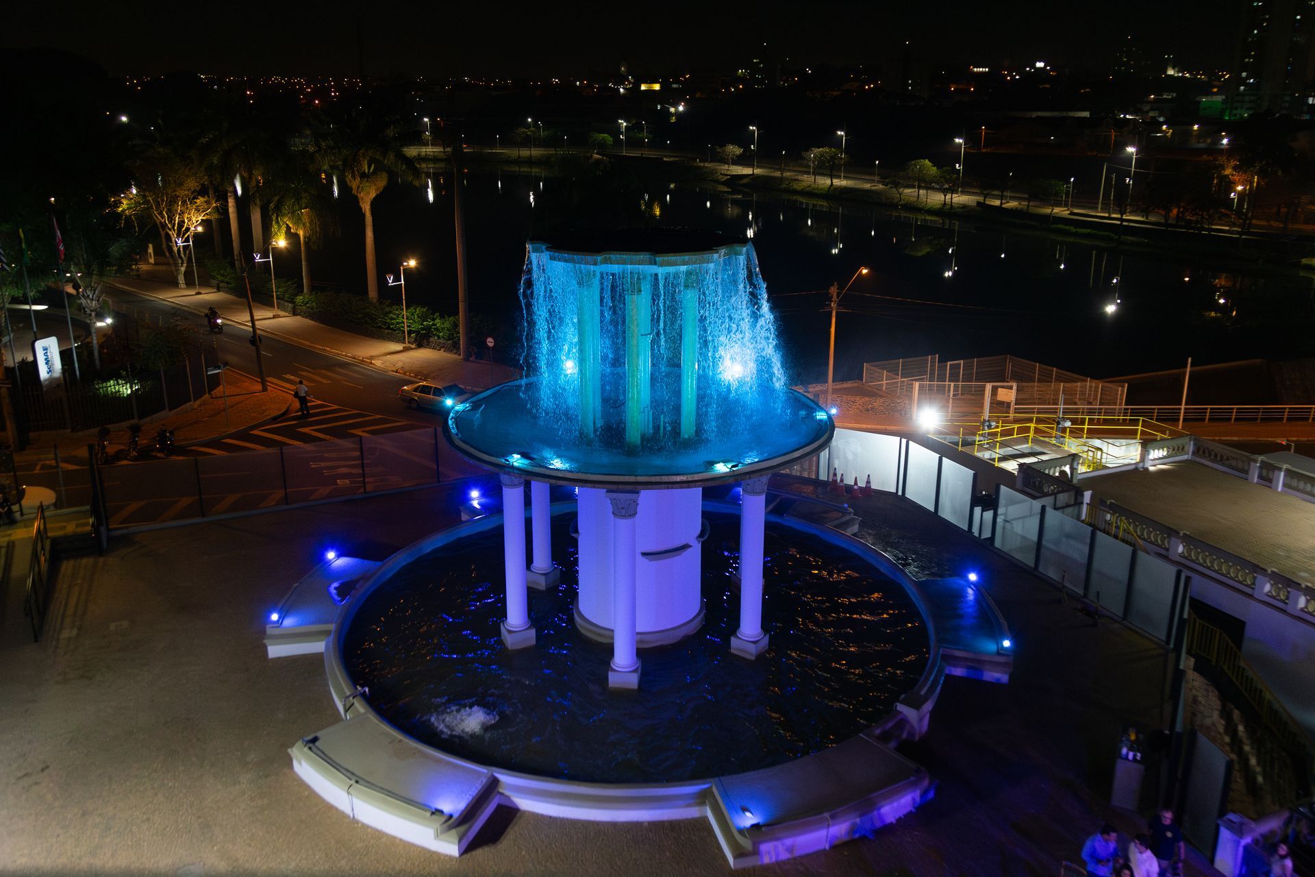 Uma vista aérea de uma fonte iluminada à noite.