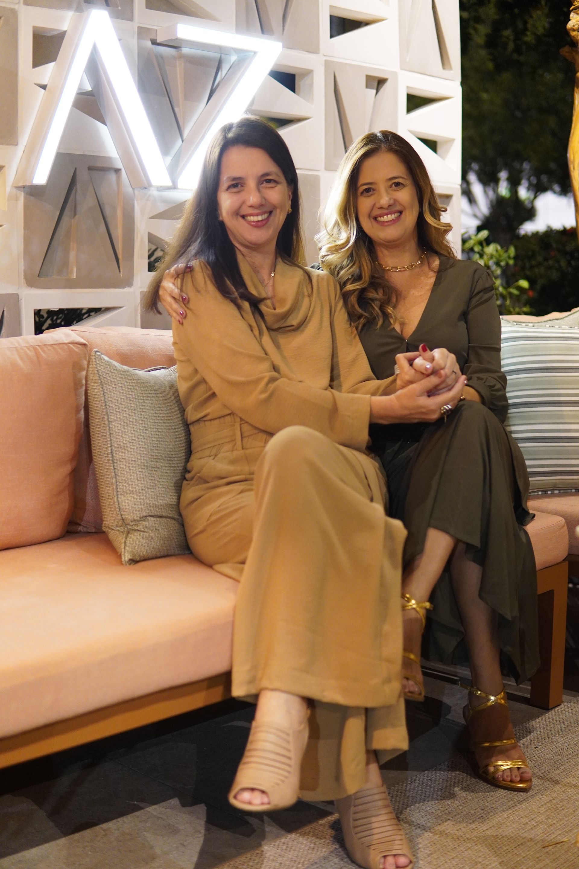 Duas mulheres estão sentadas uma ao lado da outra em um sofá.