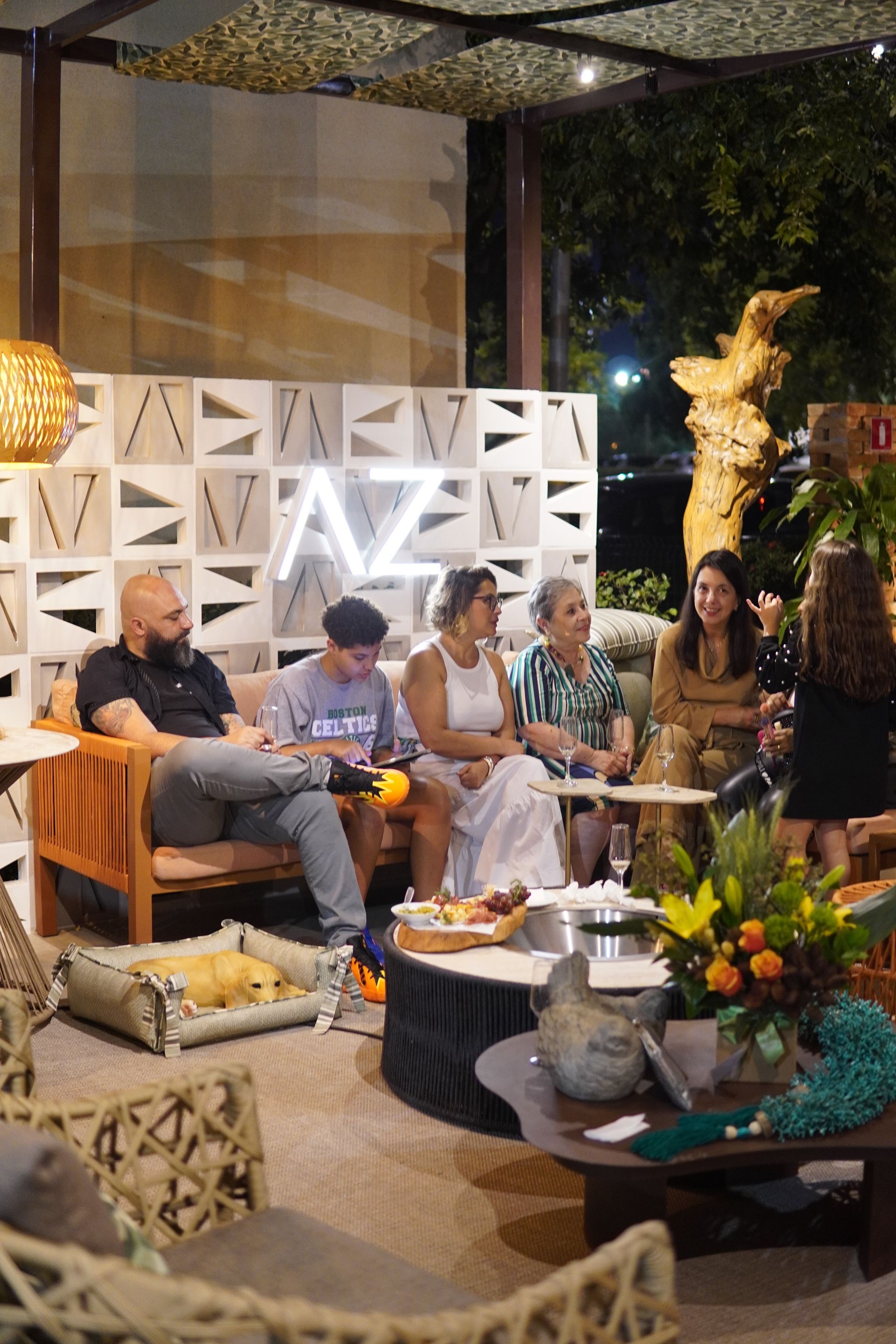 Um grupo de pessoas está sentado ao redor de uma mesa em uma sala de estar.