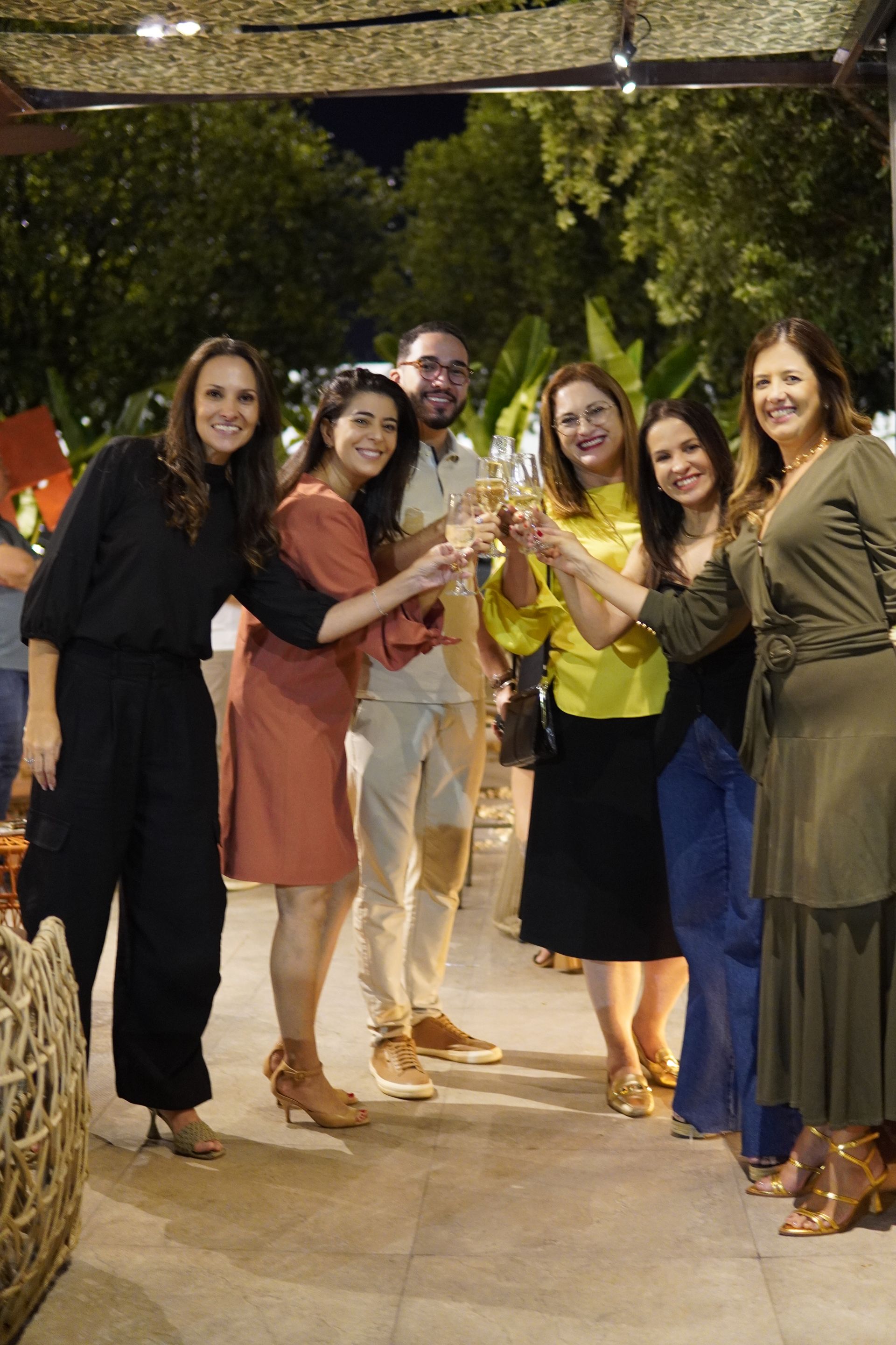 Um grupo de pessoas estão de pé, uma ao lado da outra, brindando com champanhe.