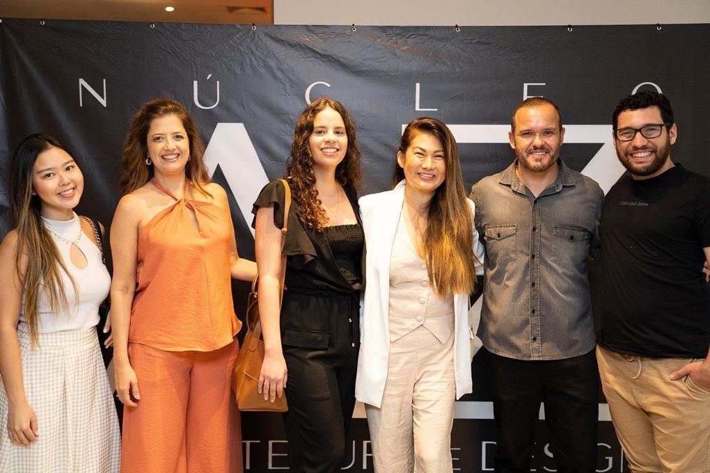 Um grupo de pessoas está posando para uma foto em frente a um banner.