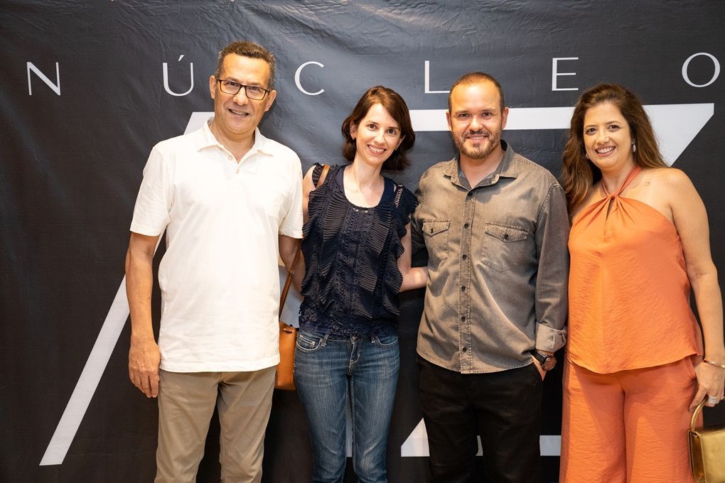 Um grupo de pessoas está posando para uma foto em frente a uma placa que diz nucleo