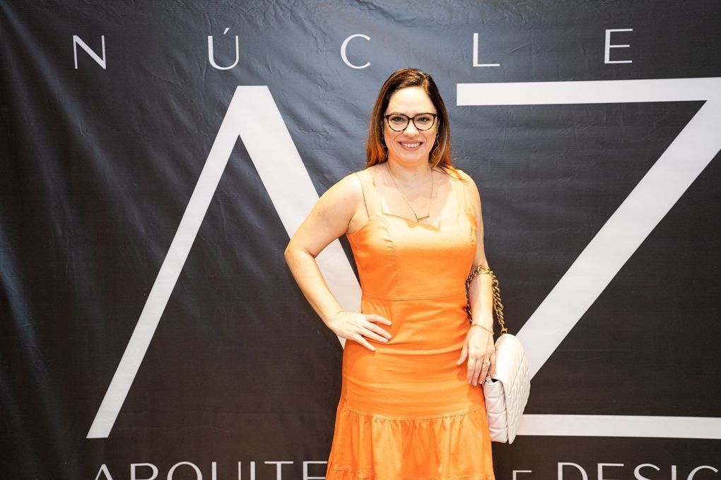 Uma mulher com um vestido laranja está em frente a uma placa que diz nuclear