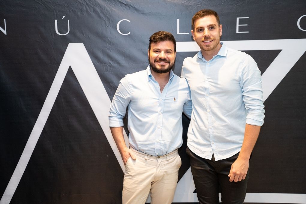 Dois homens estão posando para uma foto em frente a uma placa que diz nuclear