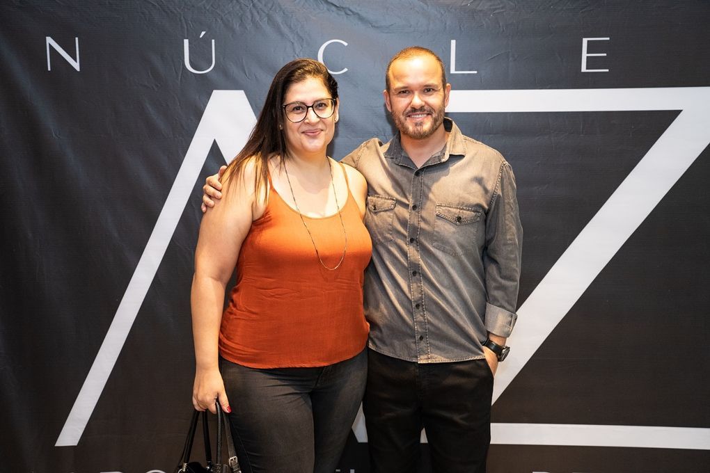 Um homem e uma mulher estão posando para uma foto em frente a uma placa que diz núcleos