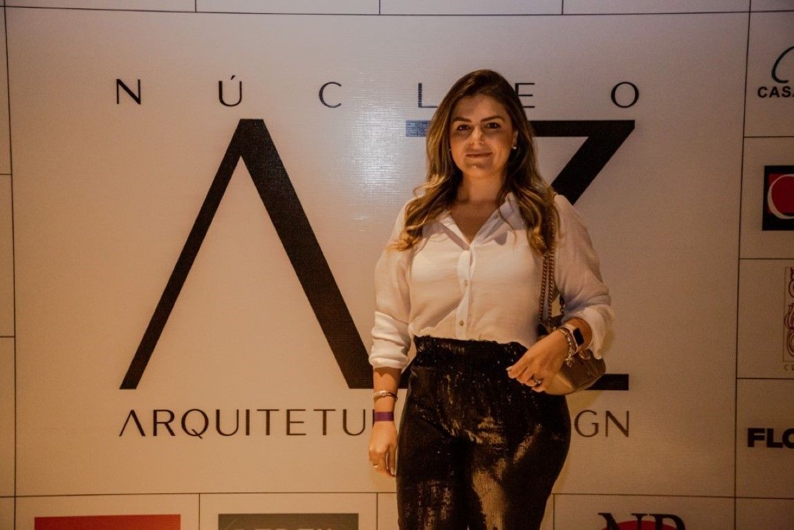 Uma mulher está parada em frente a uma placa que diz nucleo arquiteto