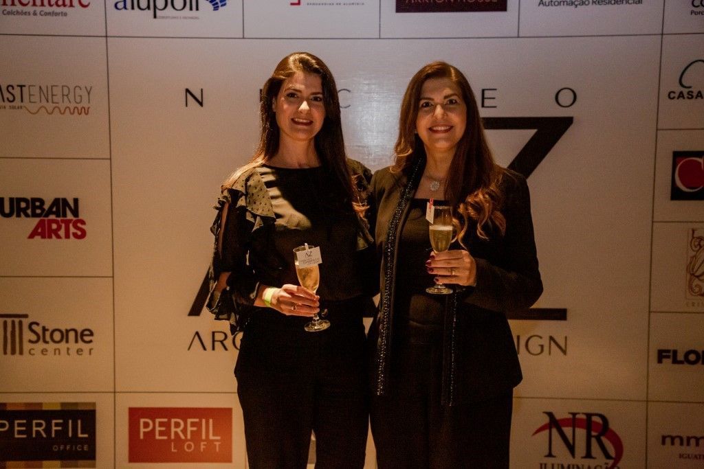 Duas mulheres em pé em frente a uma parede com logotipos para artes urbanas e perfil loft