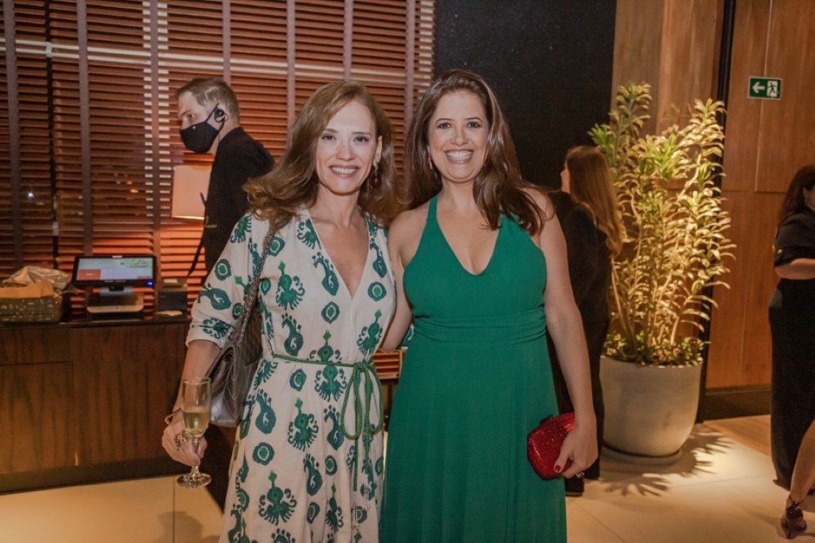 Duas mulheres em vestidos verdes estão posando para uma foto juntas.