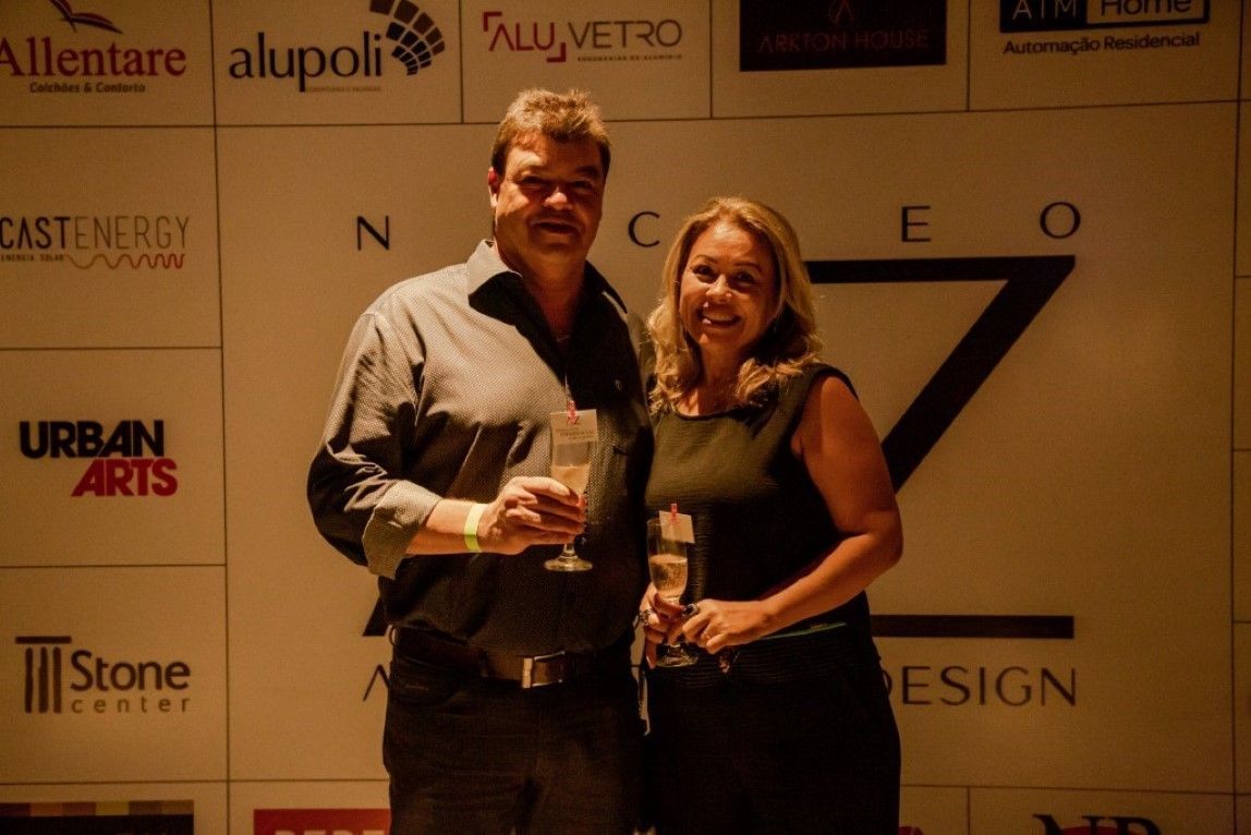 Um homem e uma mulher estão em frente a uma parede com logotipos de diferentes empresas