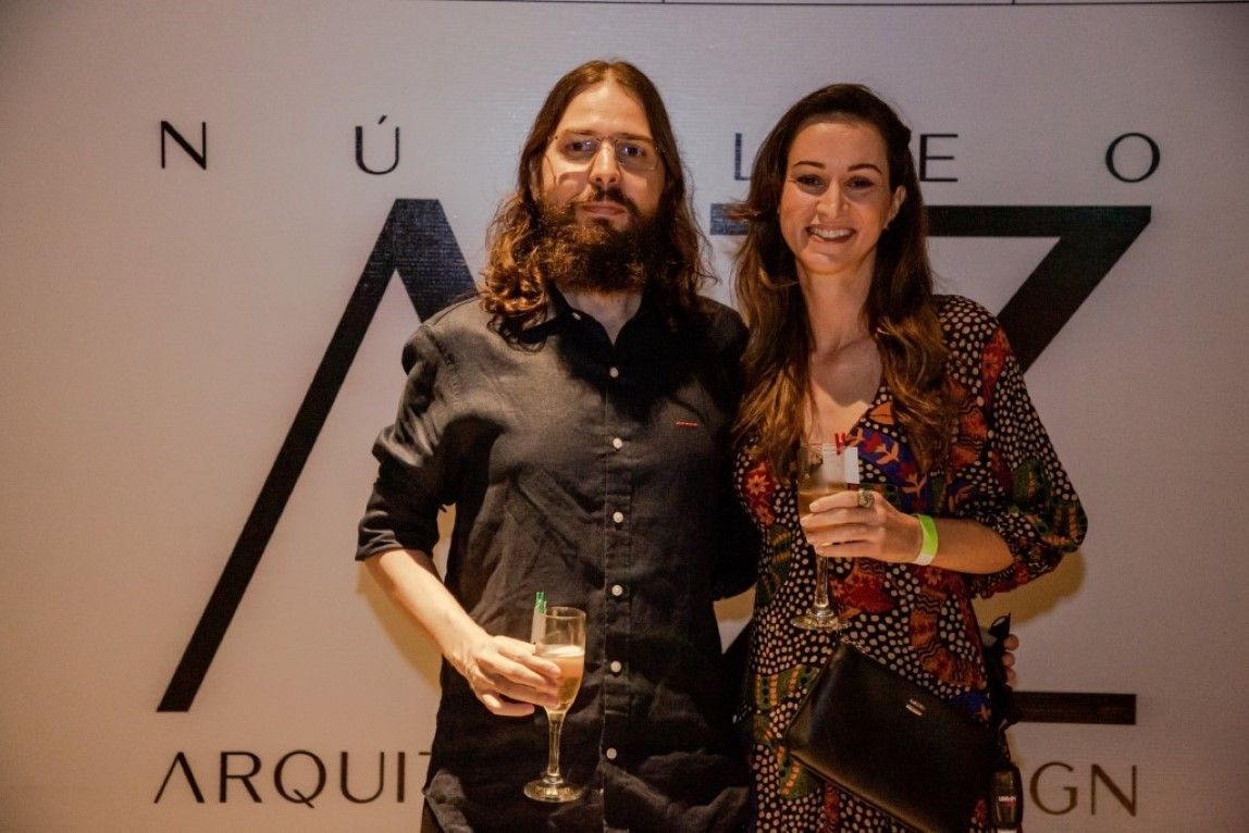 Um homem e uma mulher estão de pé, um ao lado do outro, segurando taças de vinho.