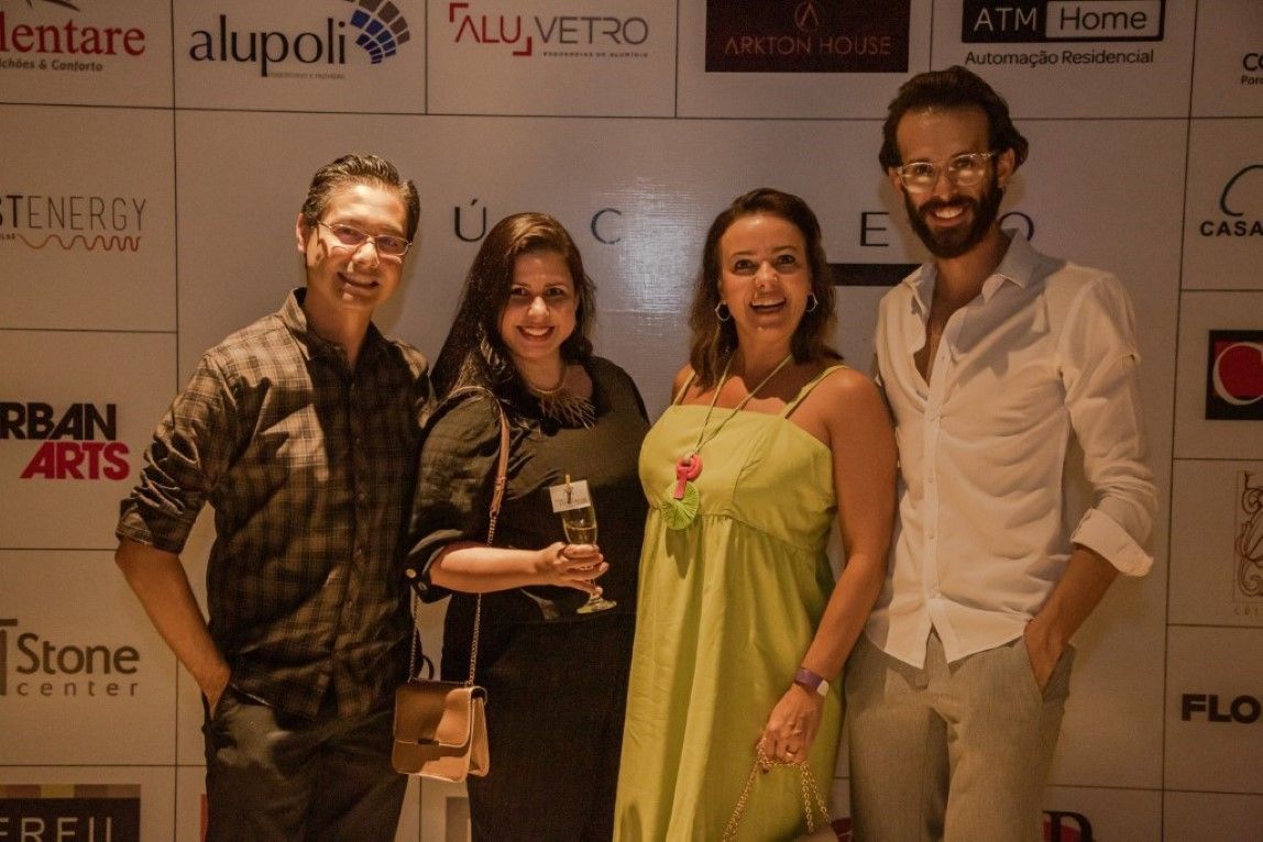 Um grupo de pessoas está posando para uma foto em frente a uma parede com logotipos.