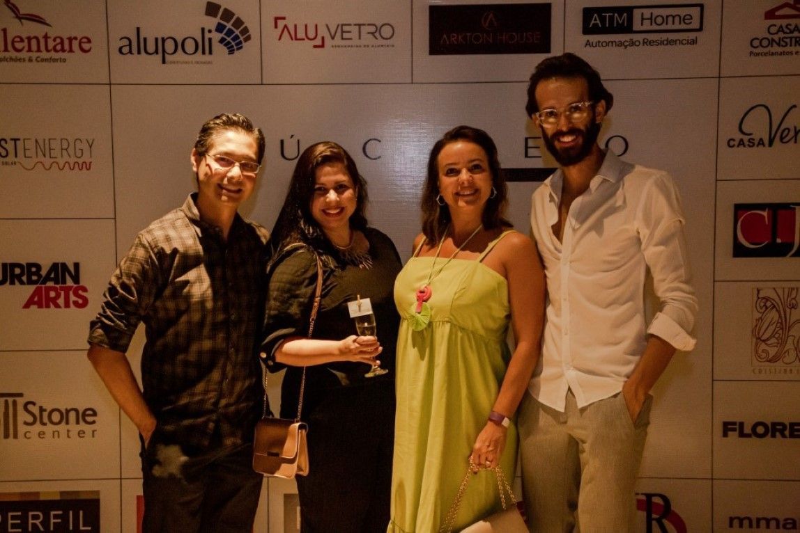 Um grupo de pessoas está posando para uma foto em frente a uma parede com logotipos.