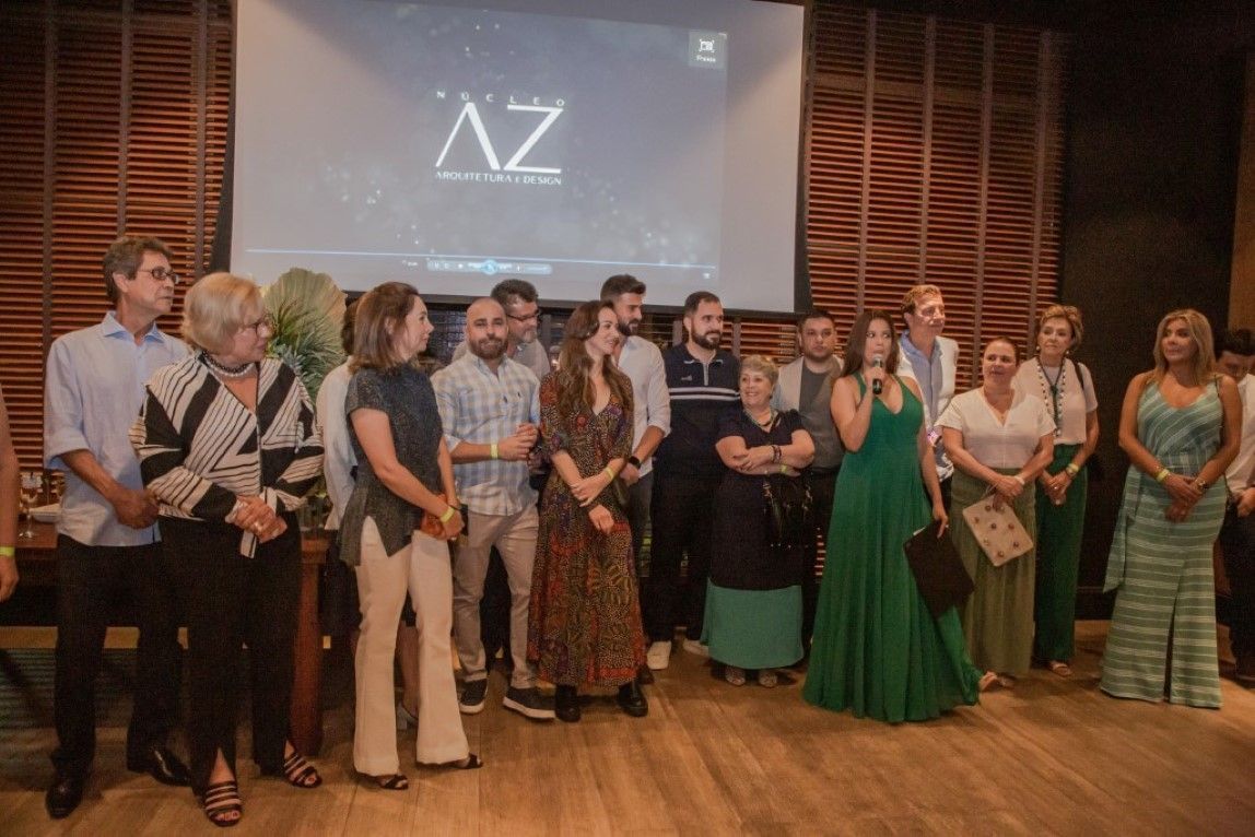 Um grupo de pessoas está em pé em frente a uma tela grande.