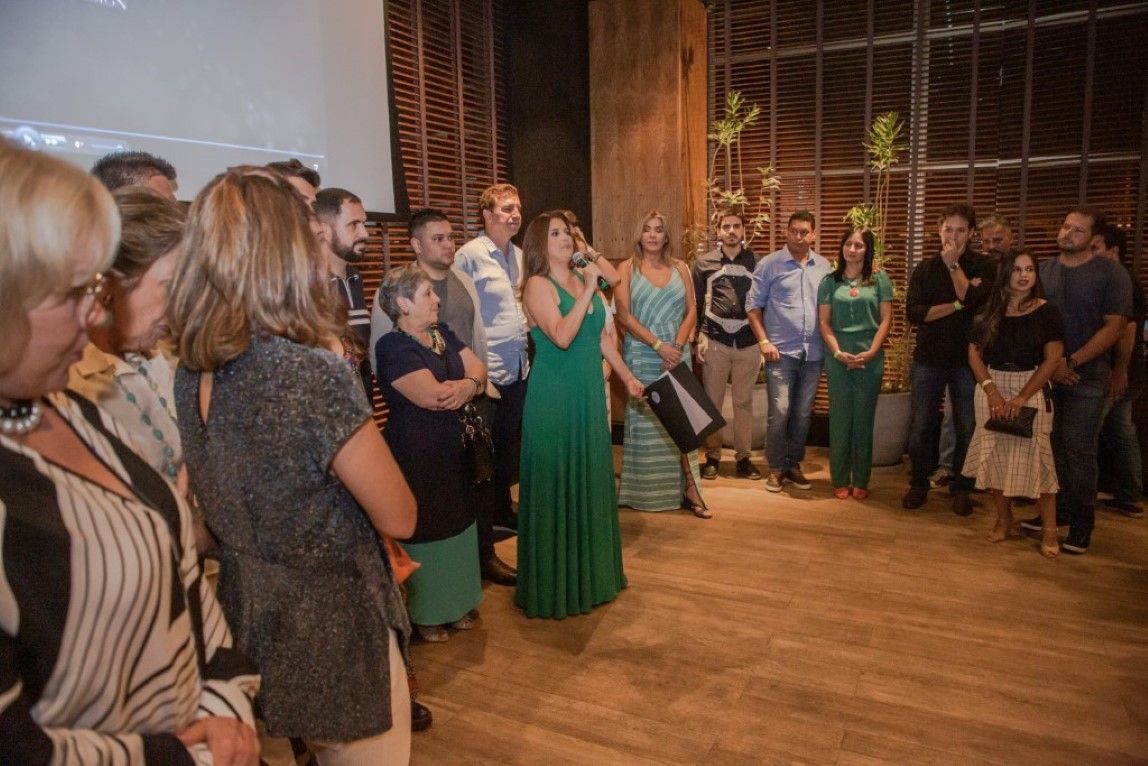 Uma mulher com um vestido verde está parada na frente de uma multidão de pessoas.