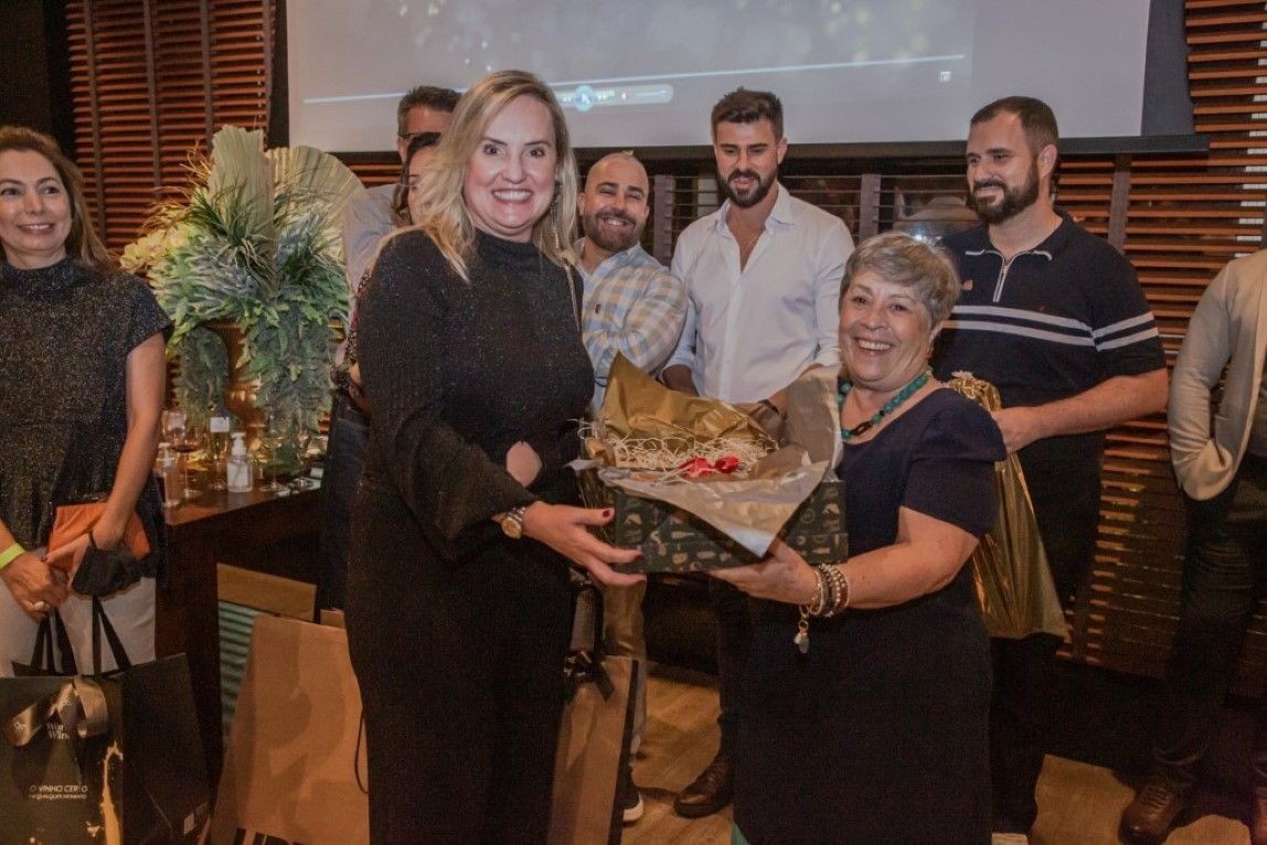 Uma mulher está segurando uma caixa de presente na frente de um grupo de pessoas.