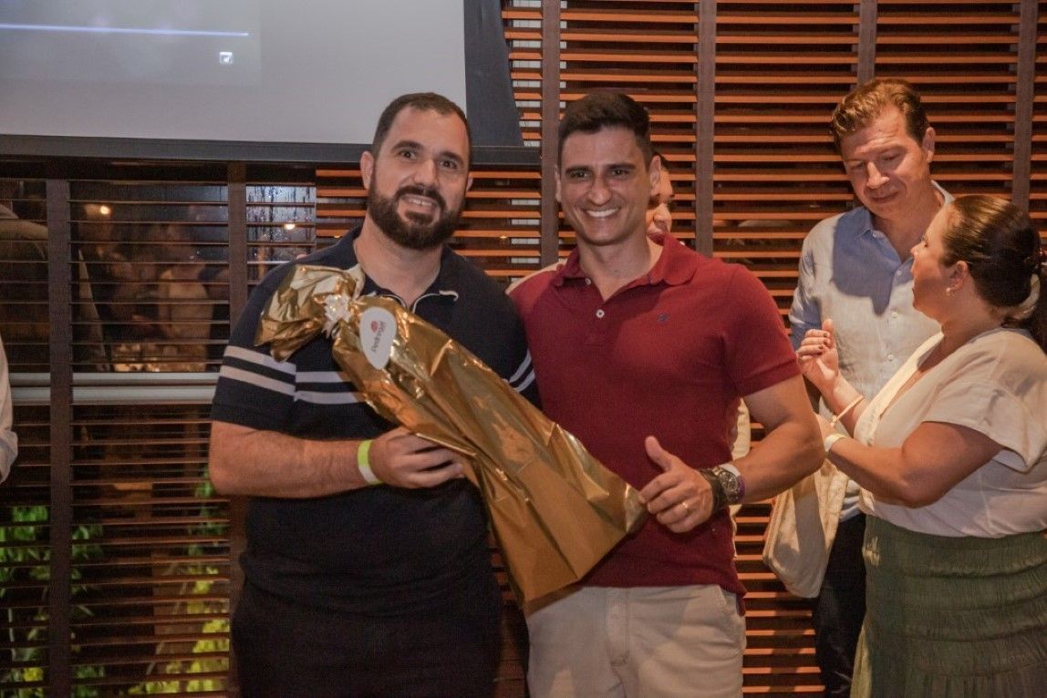 Um homem está segurando um buquê de flores e fazendo sinal de positivo enquanto está ao lado de outro homem.
